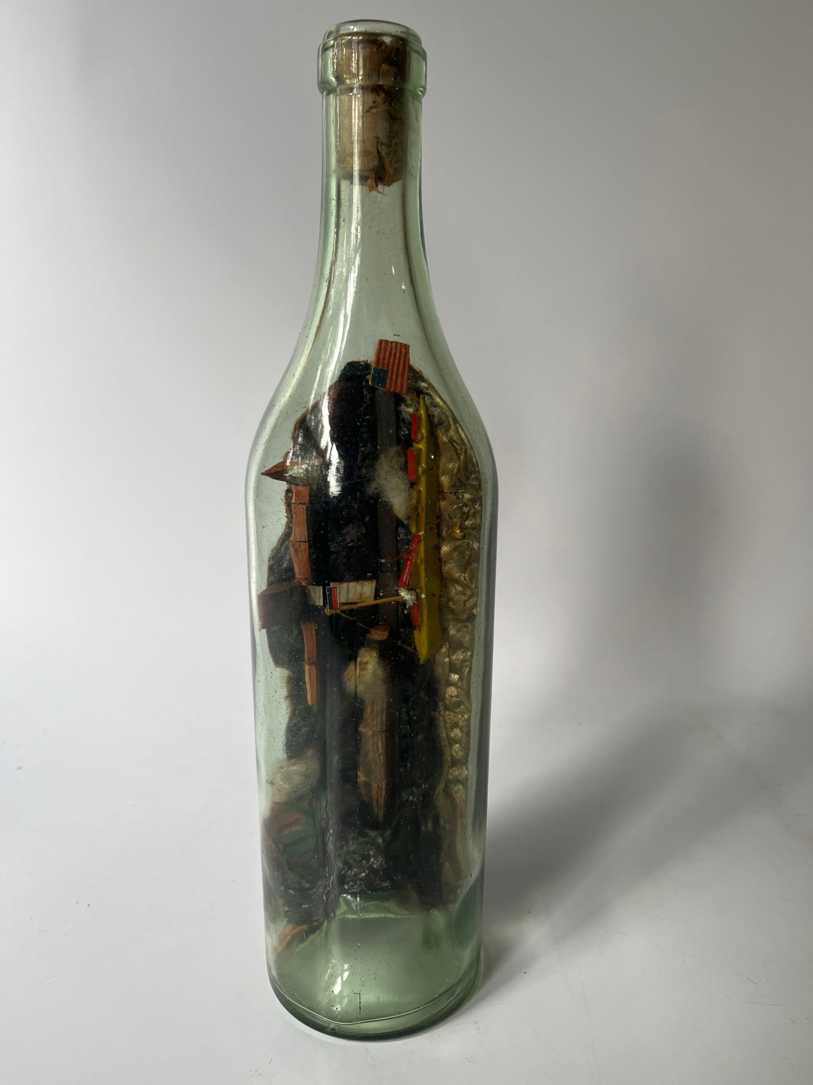 Wine bottle w/ Diorama built inside.: Here's another bottle with a scene built inside. The bottle is just a common light aqua wine bottle but the value is inside. The scene show a ship, a train leaving a tunnel with buildings in the backg