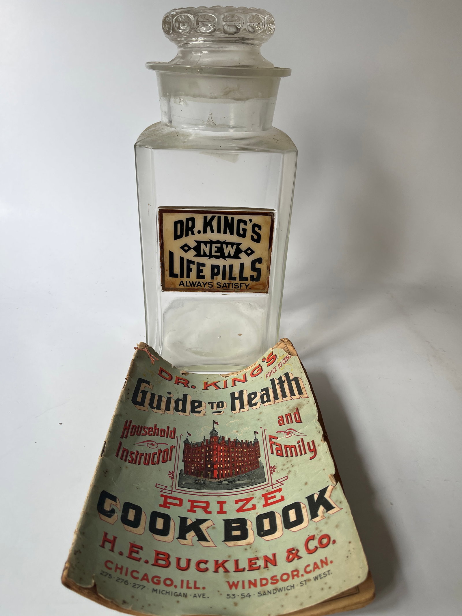 Dr. King's New Life Pills Always Satisfy store counter jar with lid.: This is for a Dr. King's New Life Pills Always Satisfy store counter jar with lid. The label is under glass and in great condition. The jar itself has a small chip on the lip and the lid has several u