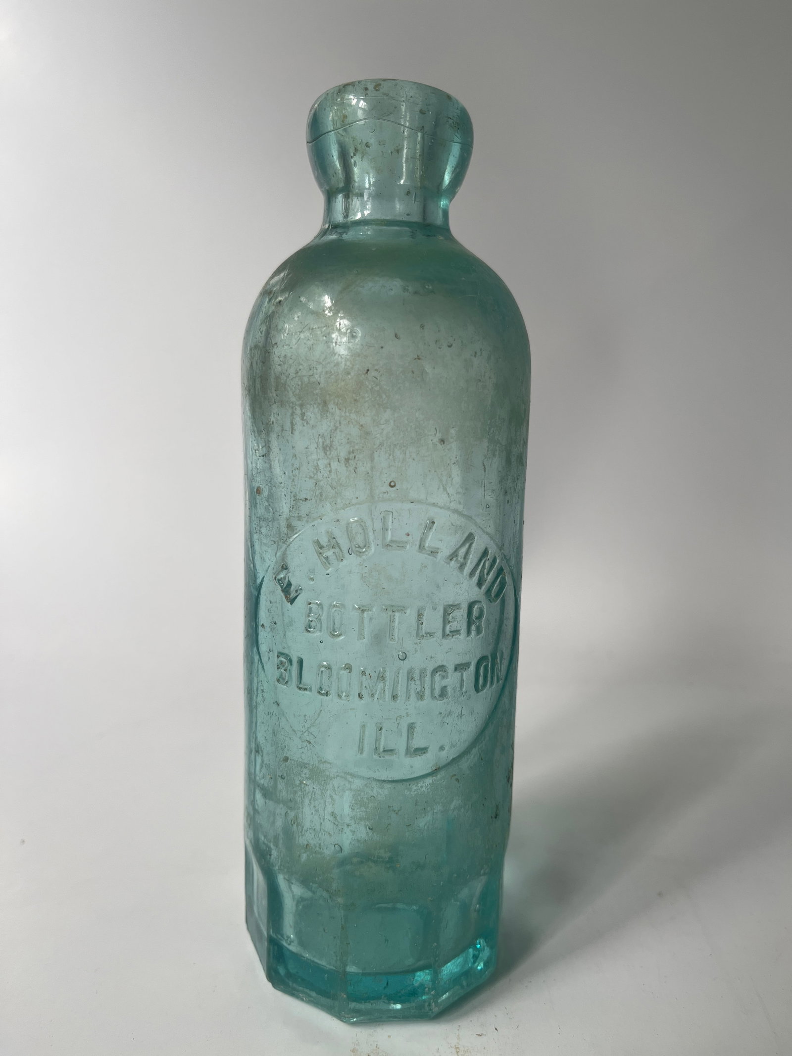 E. Holland Bottler Bloomington, Ill hutch soda: Here's an E. Holland Bottler Bloomington, Ill hutch soda. The bottle is aqua in color, has a mug base and has no damage. Just a touch of inside stain.