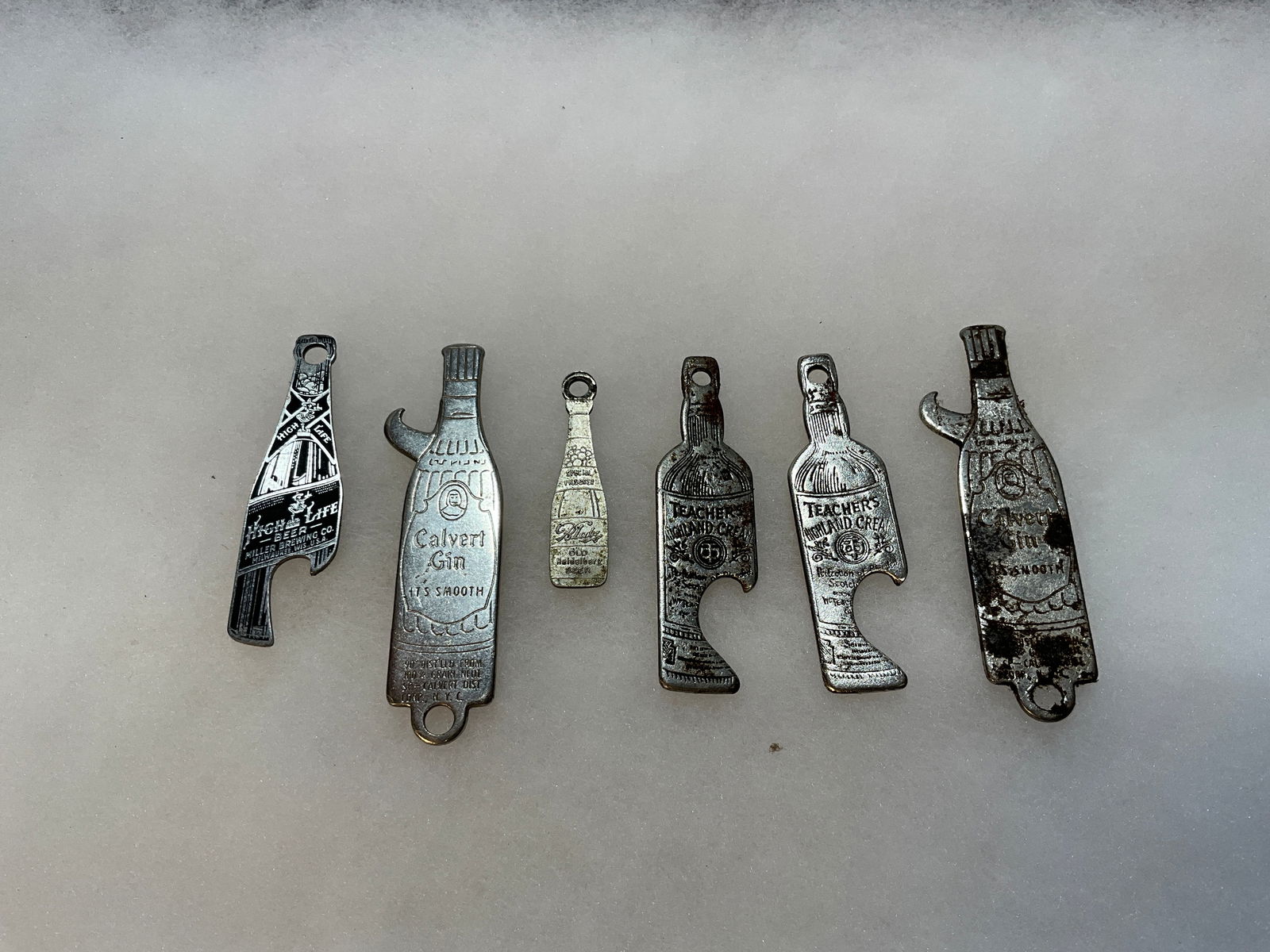 Six Early Figural Advertising Whiskey or Beer Openers in the shape of bottles (1 of 6)