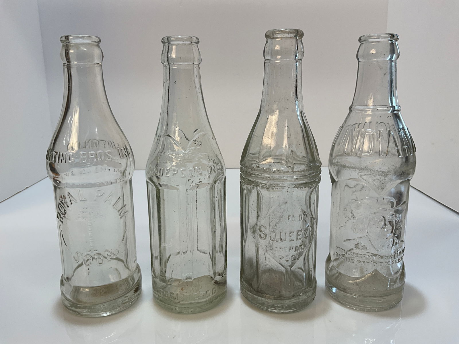 Lot of Four Art Deco Soda Pop Embossed Bottles, Linton, Anderson, Richmond & Evansville Indiana: Lot of Four Art Deco Soda Pop Embossed Bottles, Harting Bros, Royal Palm- Linton Indiana, Eagle Bottling Works - Anderson, Quaker, Coca Cola Bottling - Richmond & Squeeze - Evansville Indiana. All bot