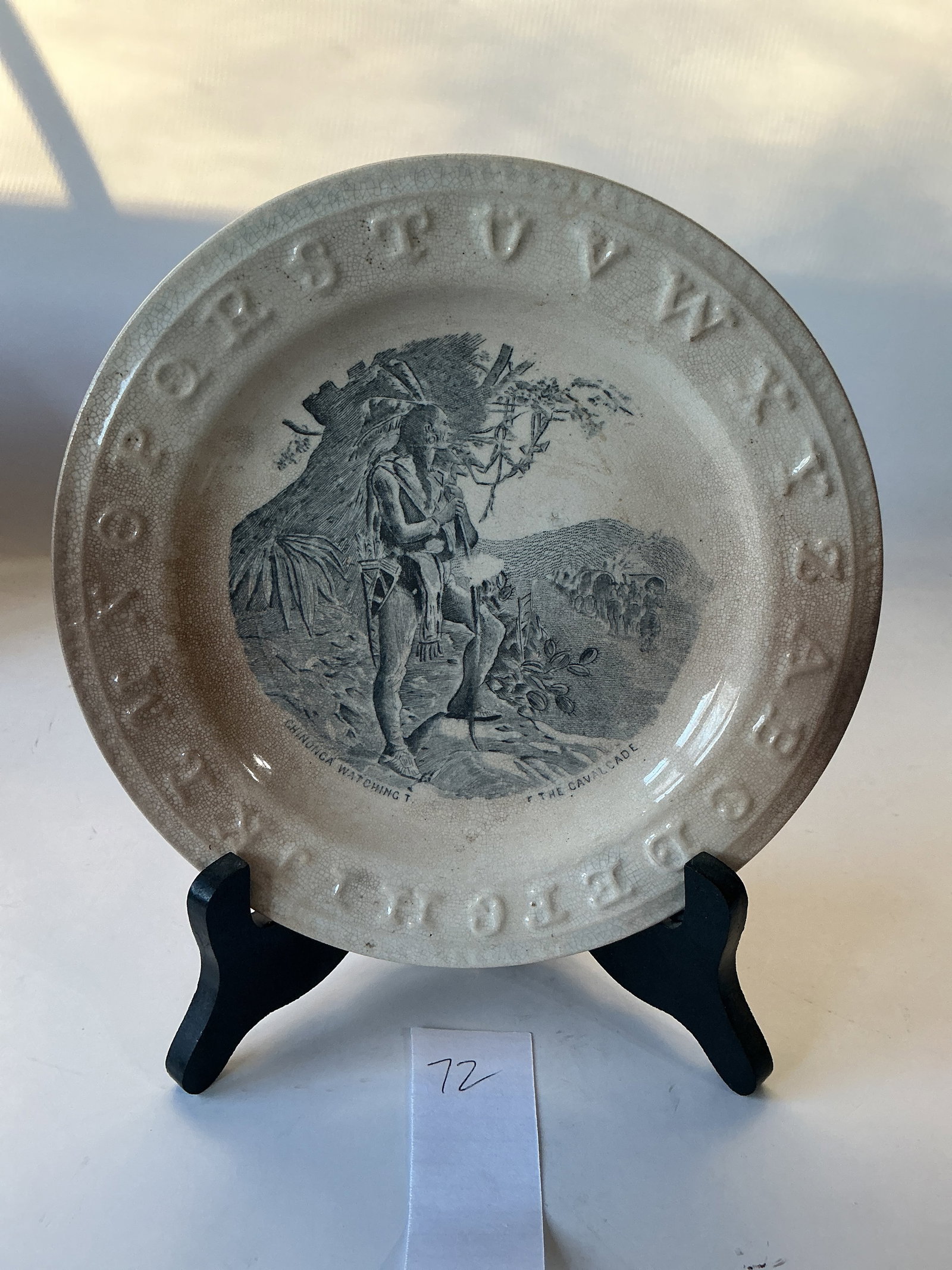 American Indians Alphabet Plate: This 7 1/2" plate, probably 1860s, is titled "Chimonea Watching the Departure of the Calvacade". (Full title not readable on this example). Printed in gray. Has brown stains and a small rim chip.