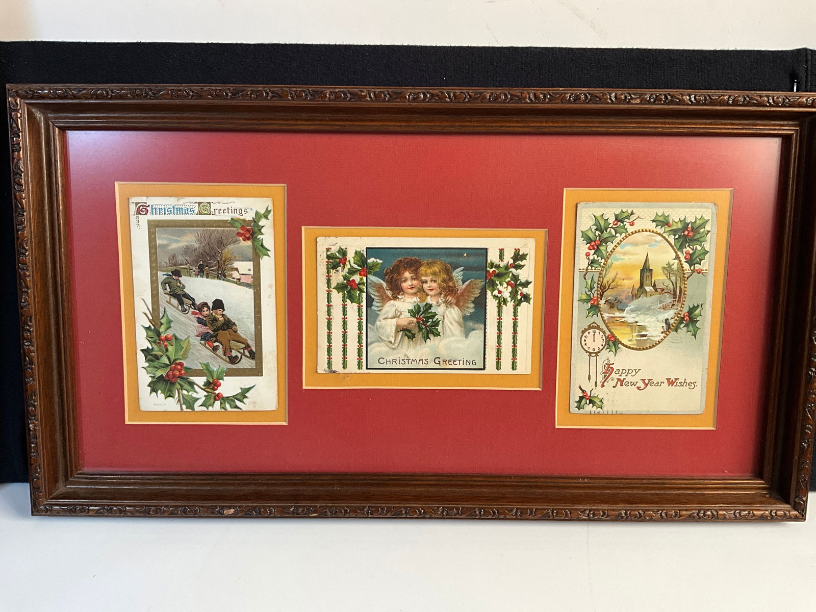 Three Framed Postcards, Christmas, New Year's Day: Two Christmas postcards and one New Year's Day postcard all mounted in a 10 1/2 X 19 1/4" frame. Cards are circa 1910 and appear to be in average to good condition. Mounting method unknown.