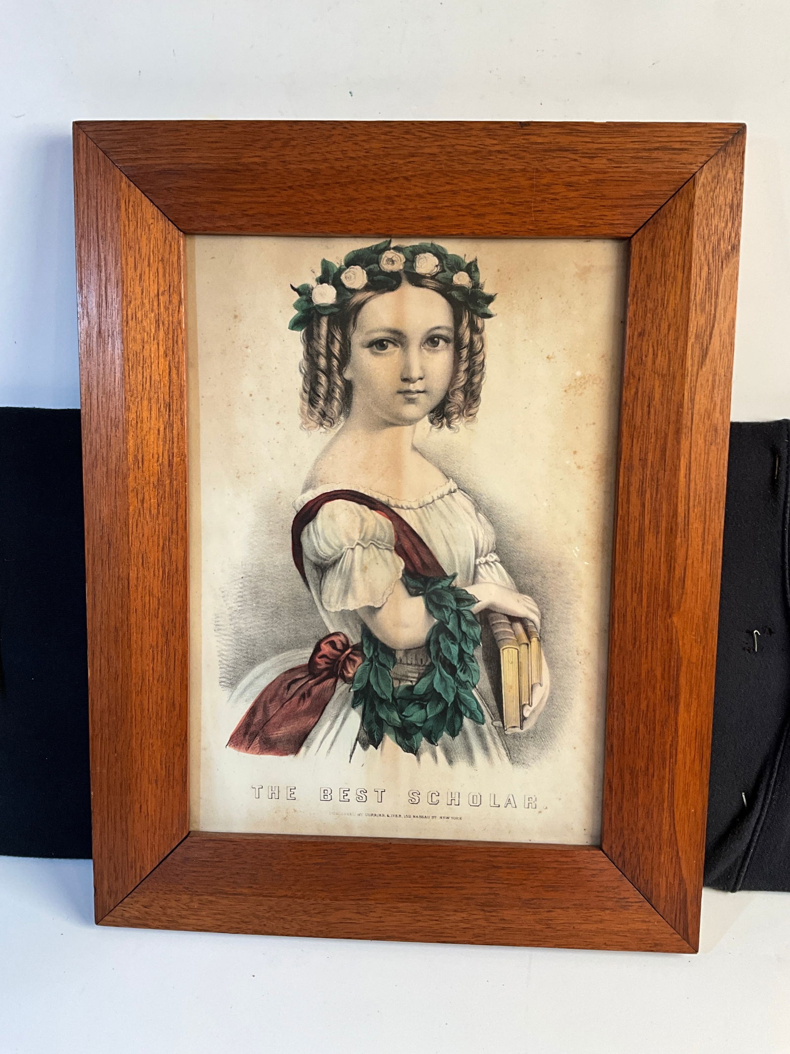 Framed Lithograph, The Best Scholar, Holding Her School Books: This is a framed, hand-tinted Currier & Ives lithograph, "The Best Scholar", circa 1870's. This idealized portrait shows a young school girl holding three books. The walnut frame (not original) measur