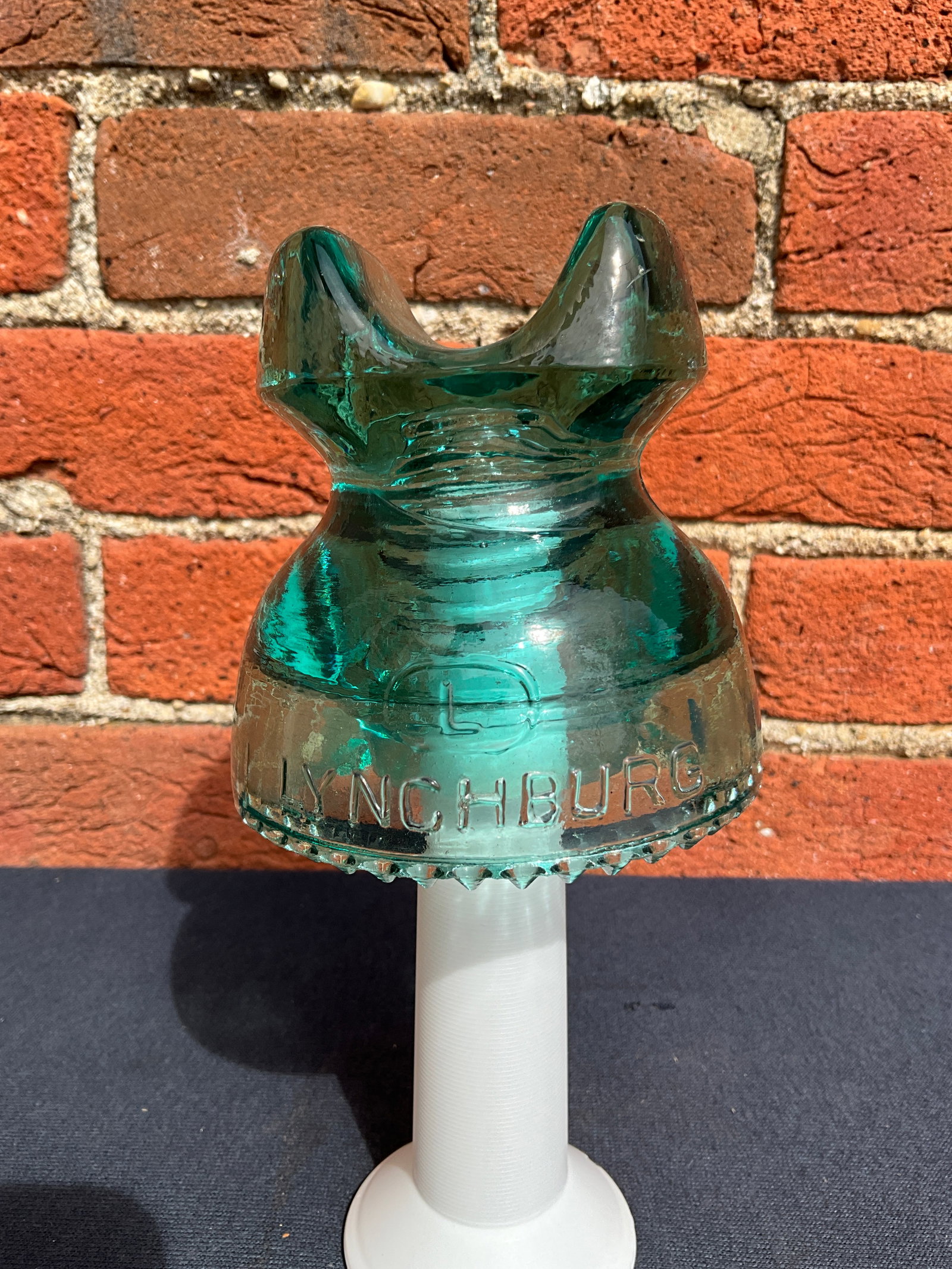 Insulator, CD 252, Embossed with L, Lynchburg, No. 2 Cable/Made in U.S.A.: This aqua Lynchburg insulator has sharp drip points. It is embossed on the front with a circled "L", along with the maker name Lynchburg. The back is embossed with No. 2 Cable, Made in the U.S.A. Ther