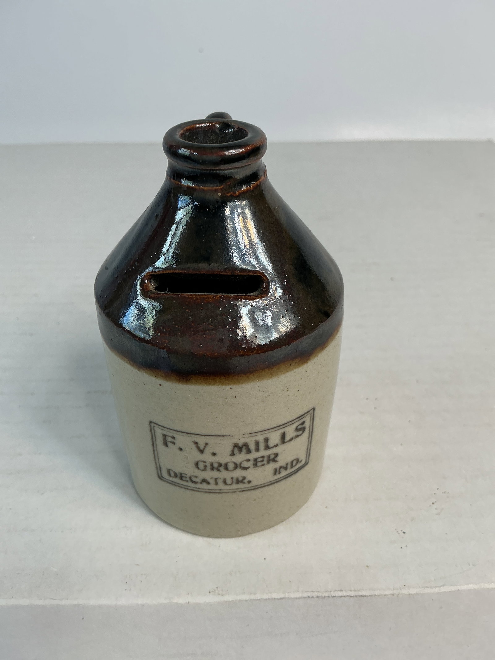 F.V. Mills Grocer Decatur, Ind Stoneware Bank: Here's a really nice stoneware advertising bank from Indiana. It is marked in black F.V. Mills Grocer Decatur, Ind. The bank stands around 4" tall, is brown over cream in color and is in perfect condi
