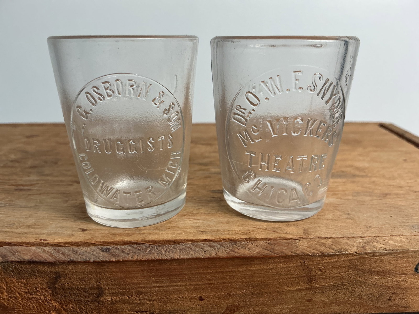2 Embossed Dose Glasses - Dr. Snyder Chicage & CG Osborn Coldwater, Mich: The first dose cup is embossed Dr. OWF Snyder McVickers Theater Chicage and the second is embossed ZG Osborn & Son Druggists Coldwater, Mich. Both are in great condition.