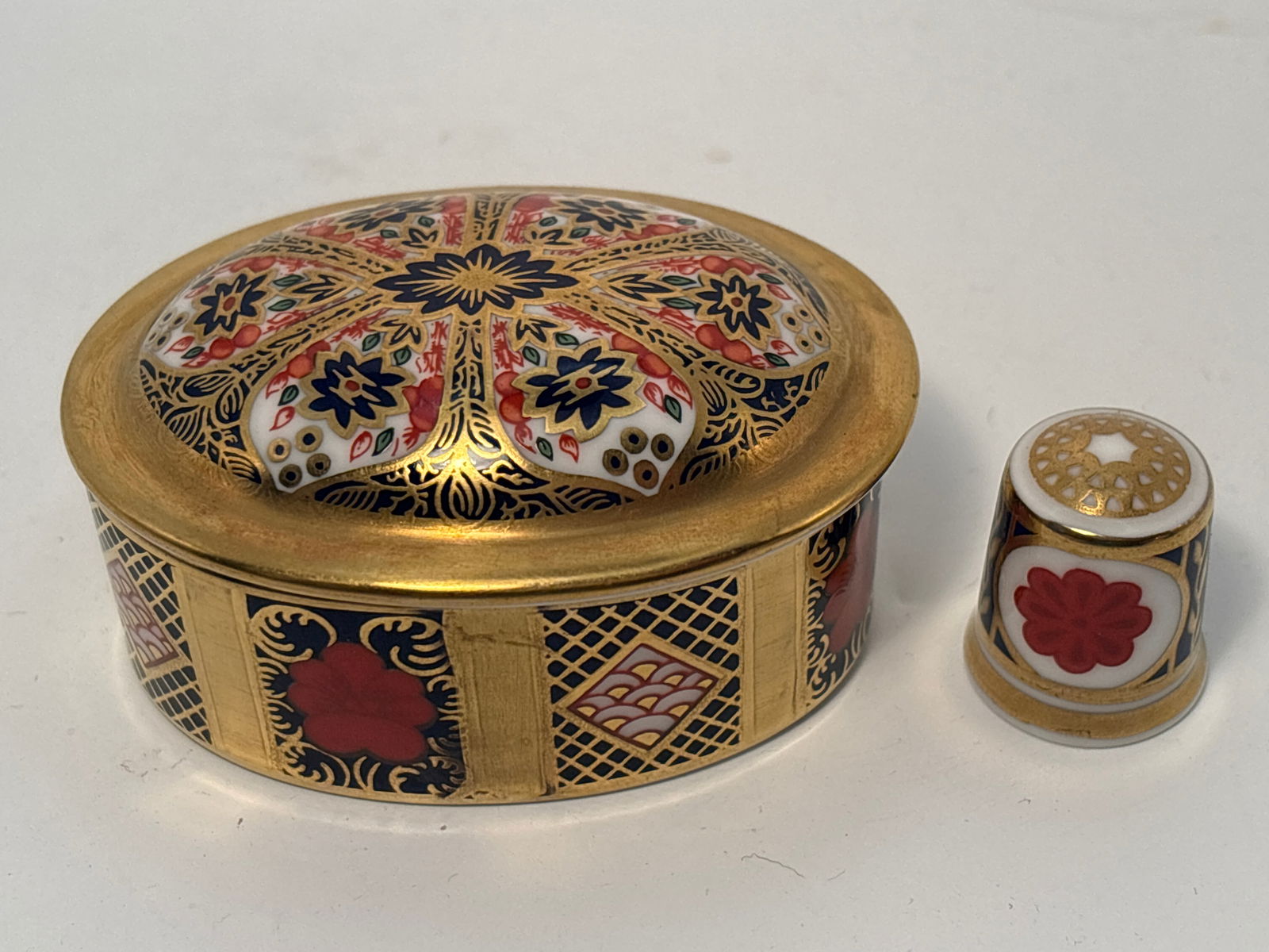 Old Imari Royal Crown Derby English china trinket/pill box & thimble: Old Imari Royal Crown Derby English china trinket/pill box & thimble. The covered oval box is 1&1/2” high by almost 3 inches long. Thimble is 1 inch.Very good beautiful condition