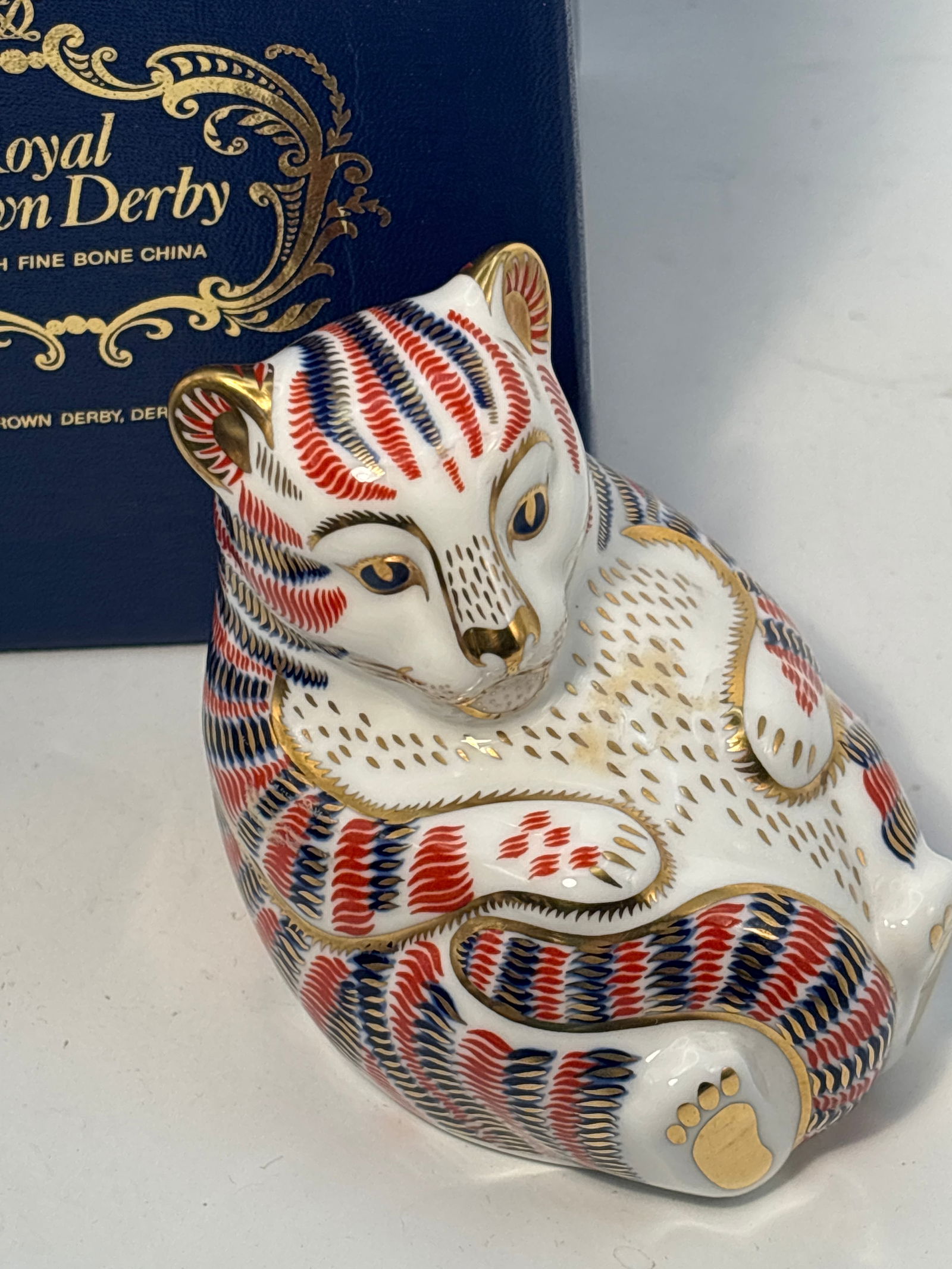 Tiger cub Royal Crown Derby English china paperweight statue: Tiger cub Royal Crown Derby Imari English china 3&1/2” paperweight.Original box (worn). Silver stopper. Very good beautiful condition