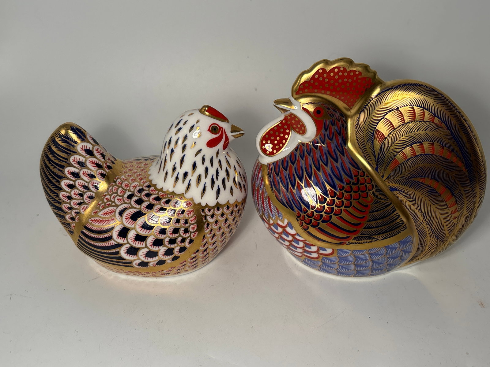 Two paperweights; Cockerel & hen Royal Crown Derby 4 inch statues: Cockerel and hen Royal Crown Derby 4 inch paperweights. Silver stopper. No box. New old stock. Very good condition