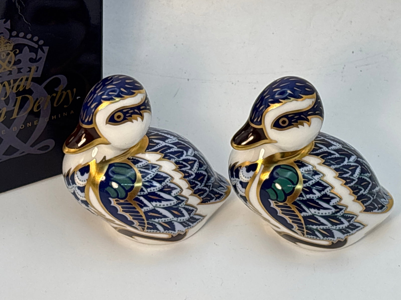 Two Swimming Ducklings blue glaze Royal Crown Derby 3 inch paperweights: Two Swimming Ducklings blue glaze Royal Crown Derby 3 inch paperweights.One gold & one silver stoppers. Only one with box.Very good condition with no chips, cracks, lines,etc