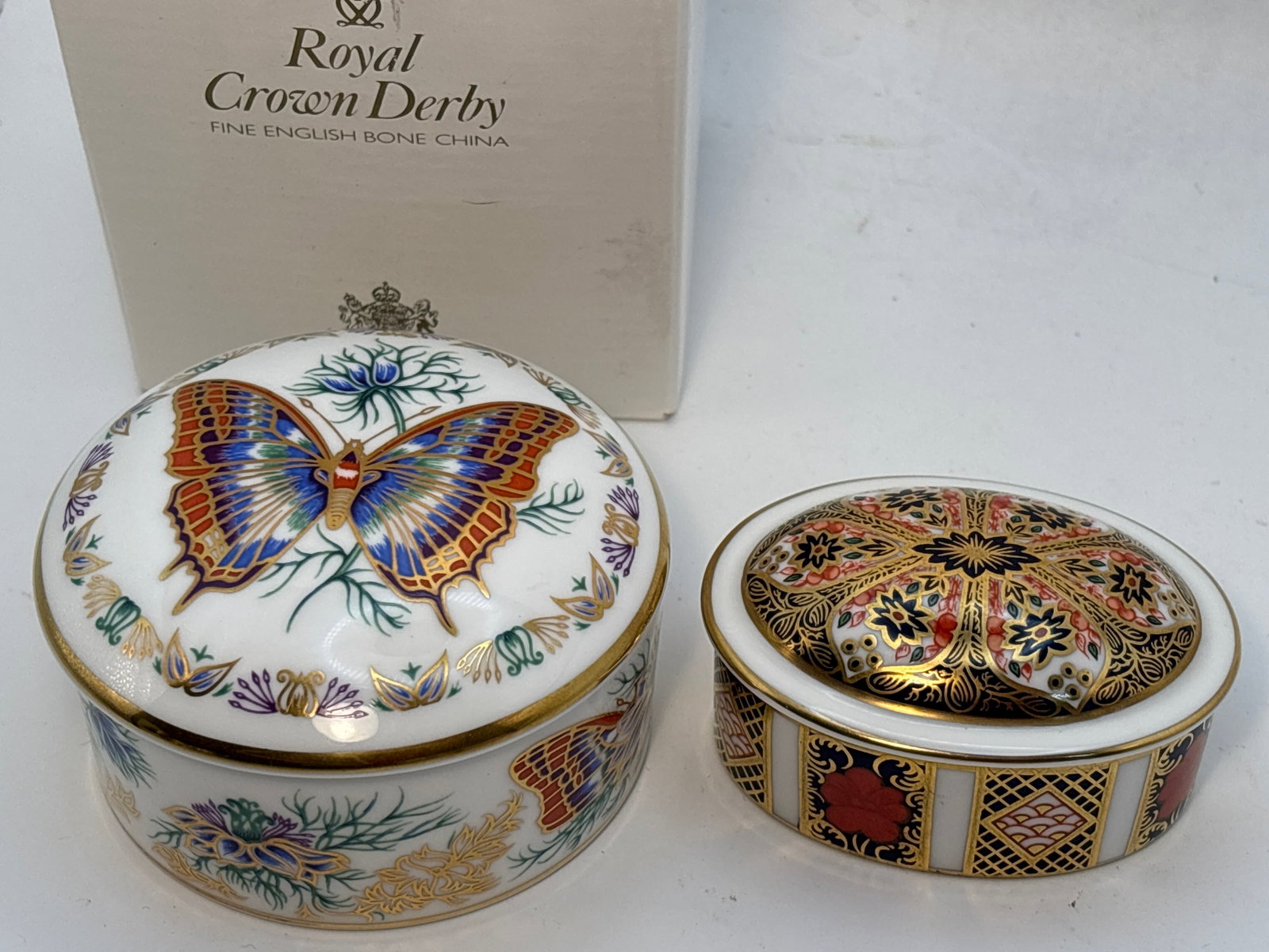 Two Royal Crown Derby England fine china covered trinket boxes: Two Royal Crown Derby England fine china covered trinket boxes. The oval Imari #1128 is 2&3/4”. The Butterflies of the World 3&1/4” circular “Europe-two-tailed Pasha” is In origina