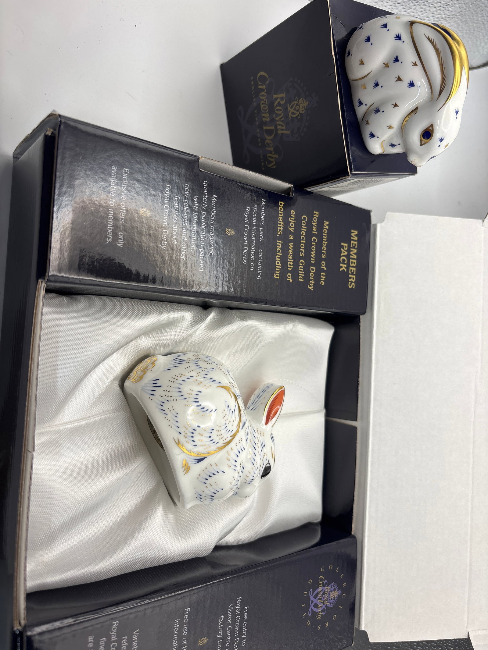 (2) An exclusive collectors guild and another rabbit Royal Crown Derby 3 inch paperweights: Two rabbits; “Bunny” exclusive collectors guild and “Baby Rabbit” Royal Crown Derby 3 inch paperweights. One boxed in Members Pack, other with box.Both gold stoppers.No chips, cracks, 