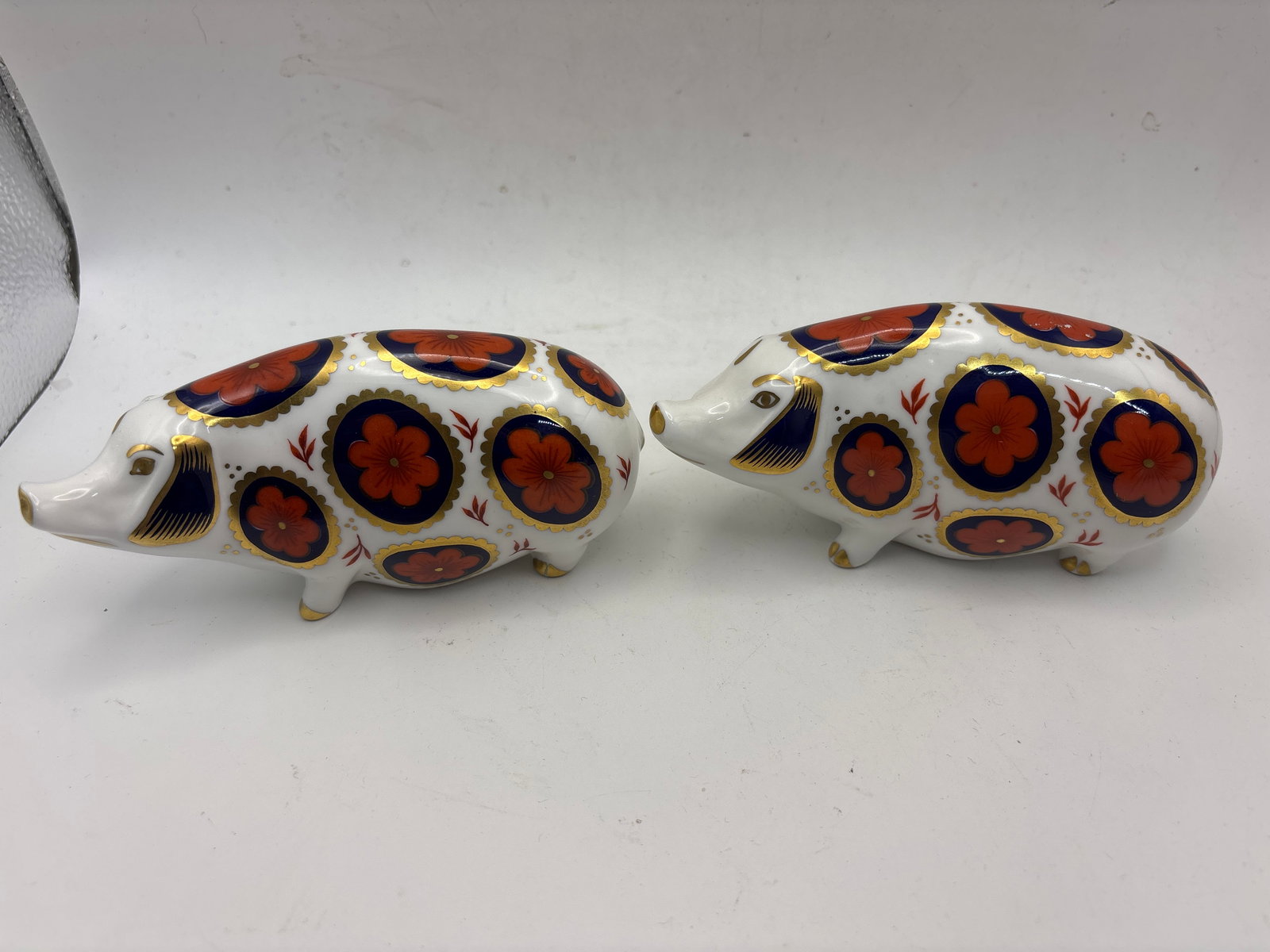 Two ‘Spotty Pig’ form Royal Crown Derby 5inch paperweights: Two “Spotty Pig” Royal Crown Derby 4&1/2 inch paperweights. One gold & one white stopper. No boxes. Very Good condition