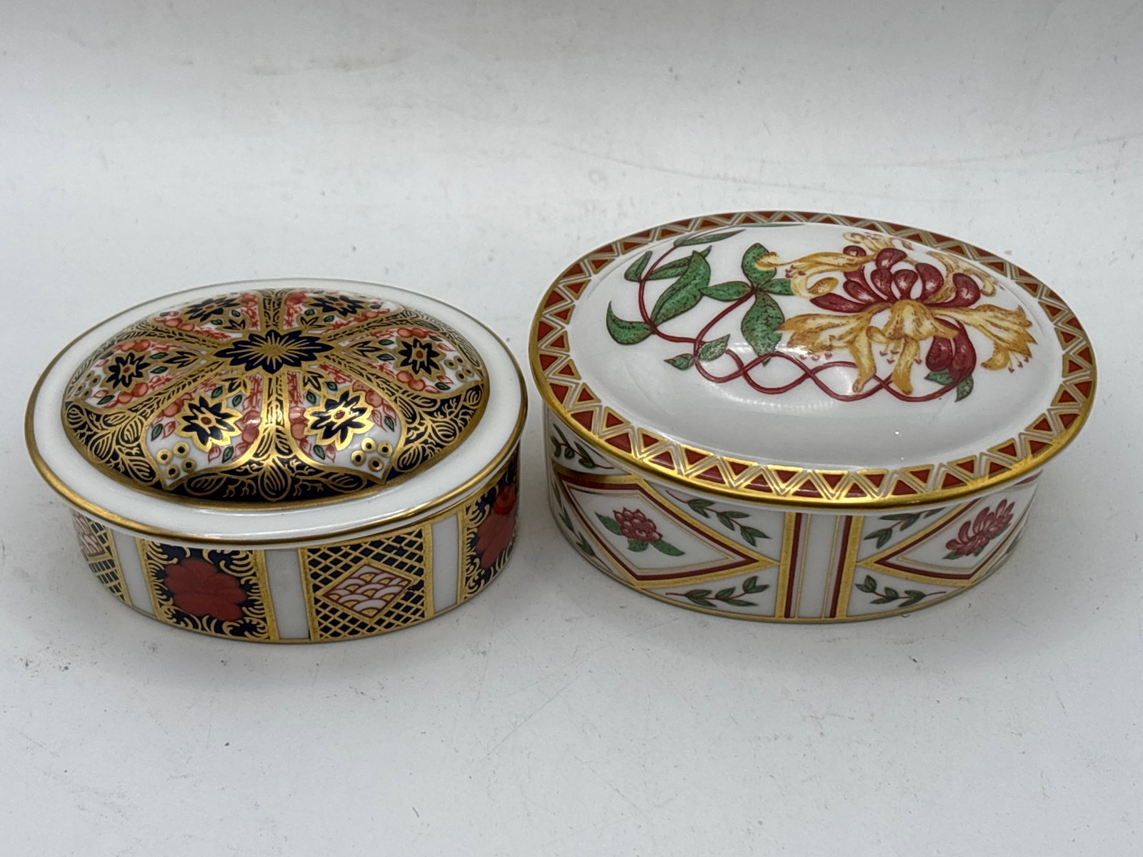 Two Royal Crown Derby oval covered trinket boxes: Imari 1128 & Honeysuckle: Two Royal Crown Derby oval covered trinket boxes: Imari 1128 & Honeysuckle. The Honeysuckle is 2&3/4 inches long and Imari is 2&1/2.Very good condition.