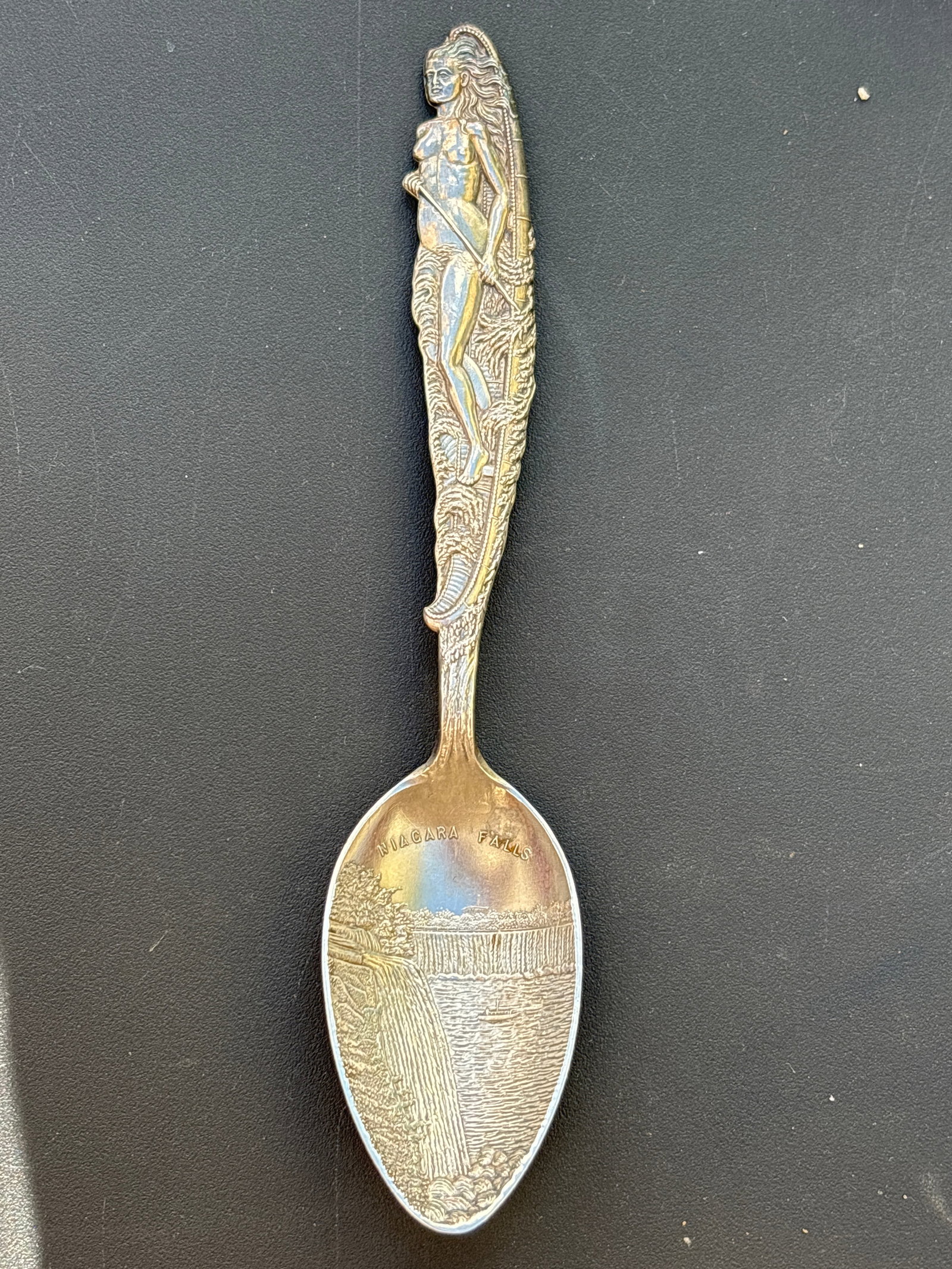 Rare female nude handle Niagara Falls sterling silver souvenir 5&3/4 inch spoon; 32 grams: Rare female nude handle Niagara Falls sterling silver souvenir 5&3/4 inch spoon; 32 grams. Figural nude in canoe handle and Falls design to bowl end.Good condition.