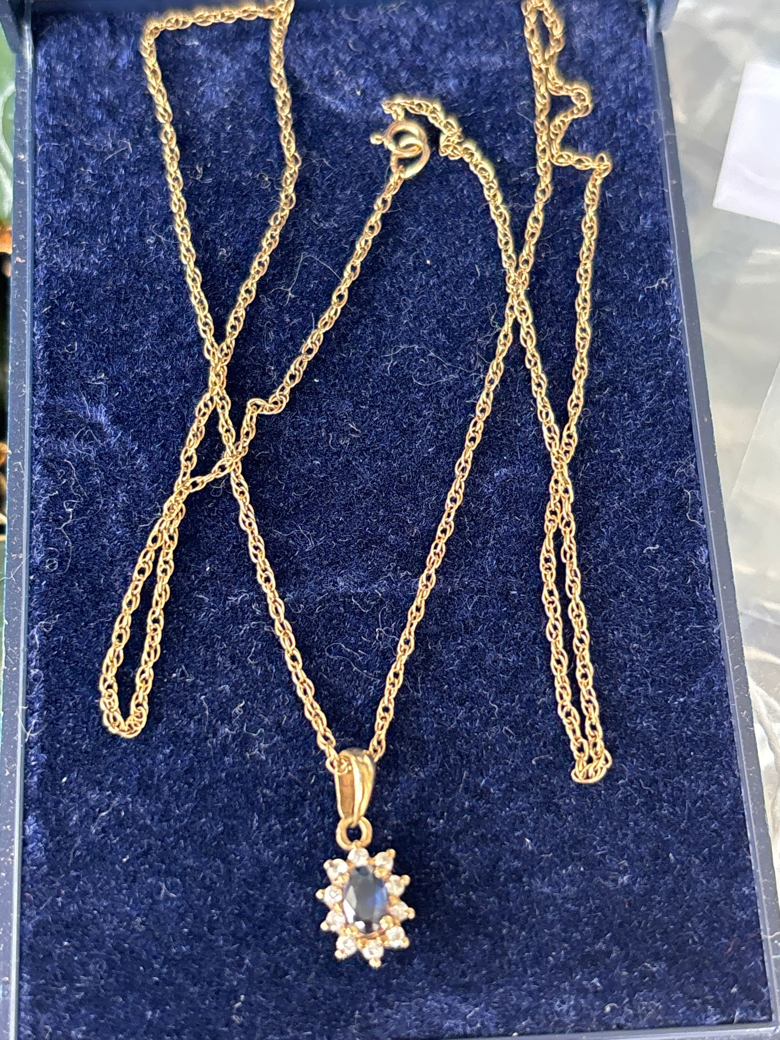 English 9ct (9k) gold sapphire and diamond cluster pendant necklace; 1.6 gram: A 9ct gold sapphire and diamond cluster pendant necklace,the pendant set with an approx. 0.15ct oval brilliant cut dark blue sapphire and a border of ten melee round brilliant cut diamonds, pendant me