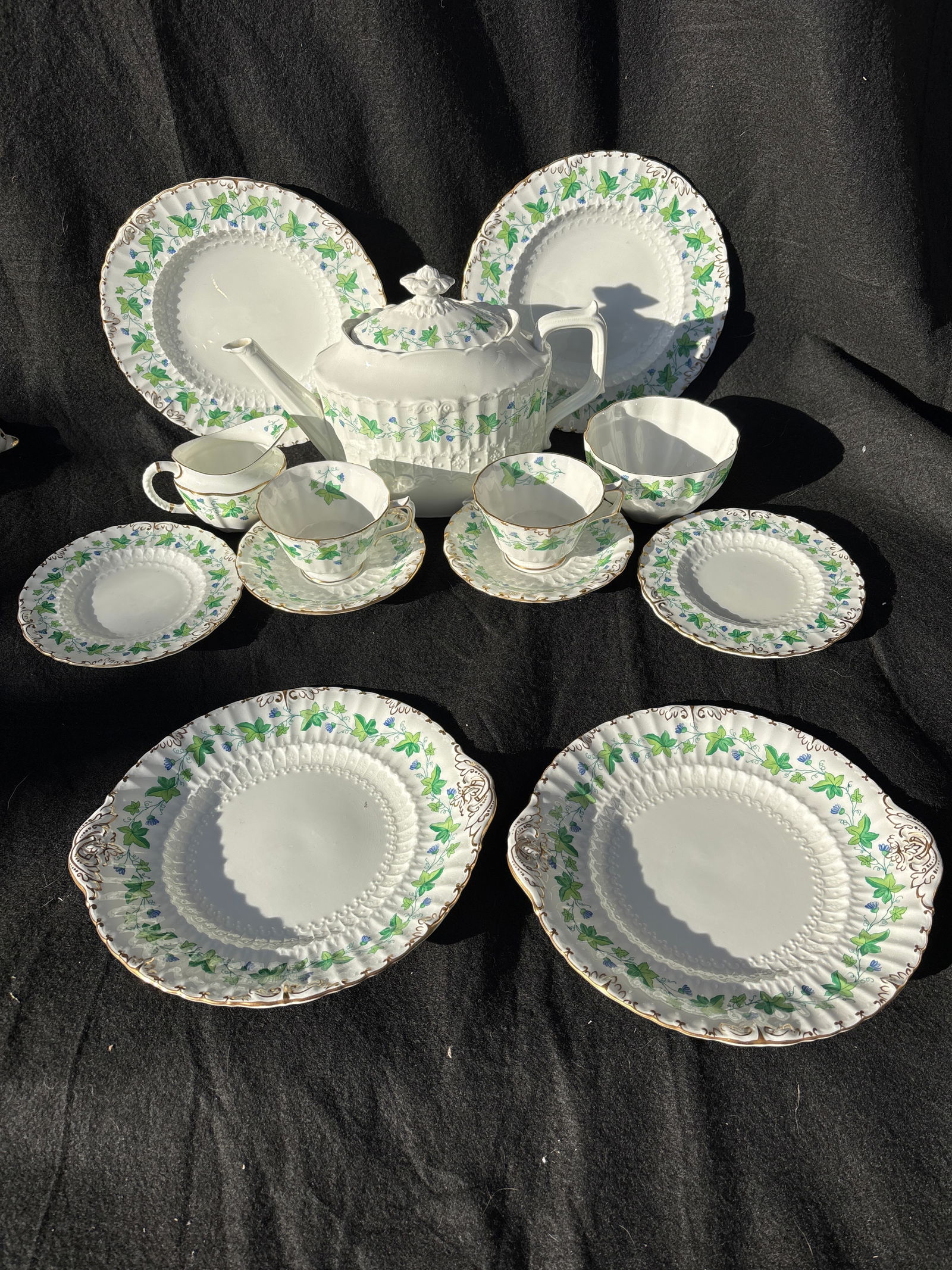 Thirteen pieces Royal Crown Derby Medway (Burford) pattern teapot set: Thirteen pieces Royal Crown Derby Medway (Burford) pattern teapot set.It features a white china body with an embossed pattern and hand-painted green ivy vines and small blue flowers. The pattern, also