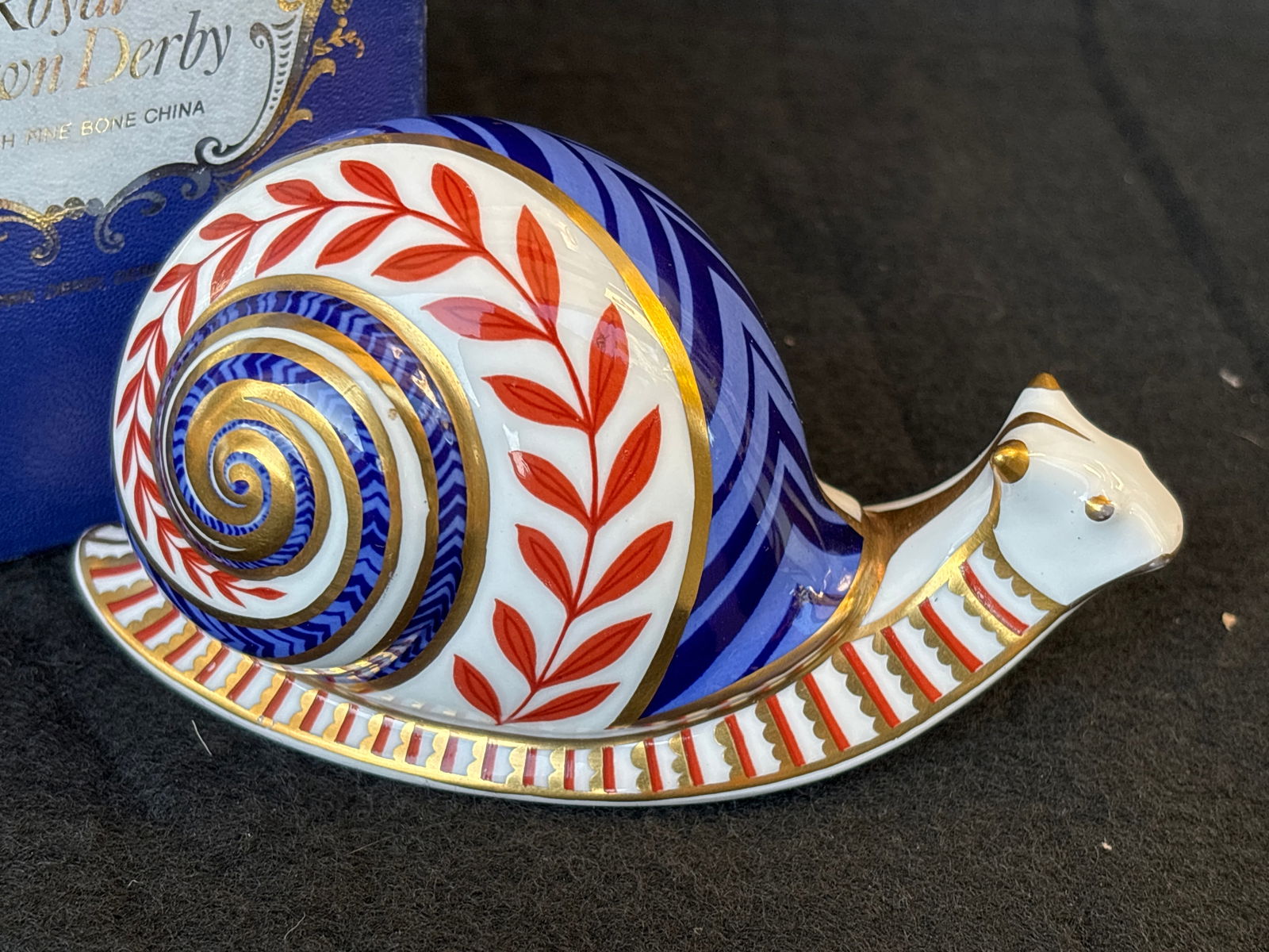 Vintage Royal Crown Derby "Old Imari" Snail form 4 inch paperweight: Royal Crown Derby snail paperweight, featuring an Imari pattern in blue, red, and gold. It is made from fine bone china and hand-decorated with 22-carat gold accents. The snail was introduced in 1985