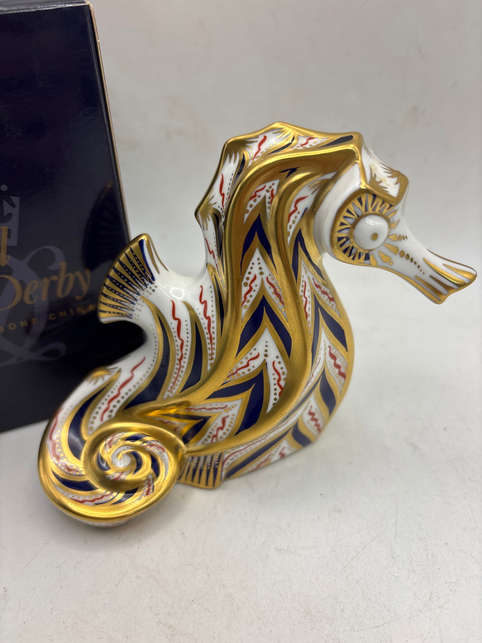 Lovely Good Band Seahorse Royal Crown Derby 4 inch paperweight: Royal Crown Derby Seahorse paperweight. It is part of the "Old Imari Solid Gold Band" collection, known for its intricate blue, red, and gold pattern. Each piece is hand-decorated and finished with ha