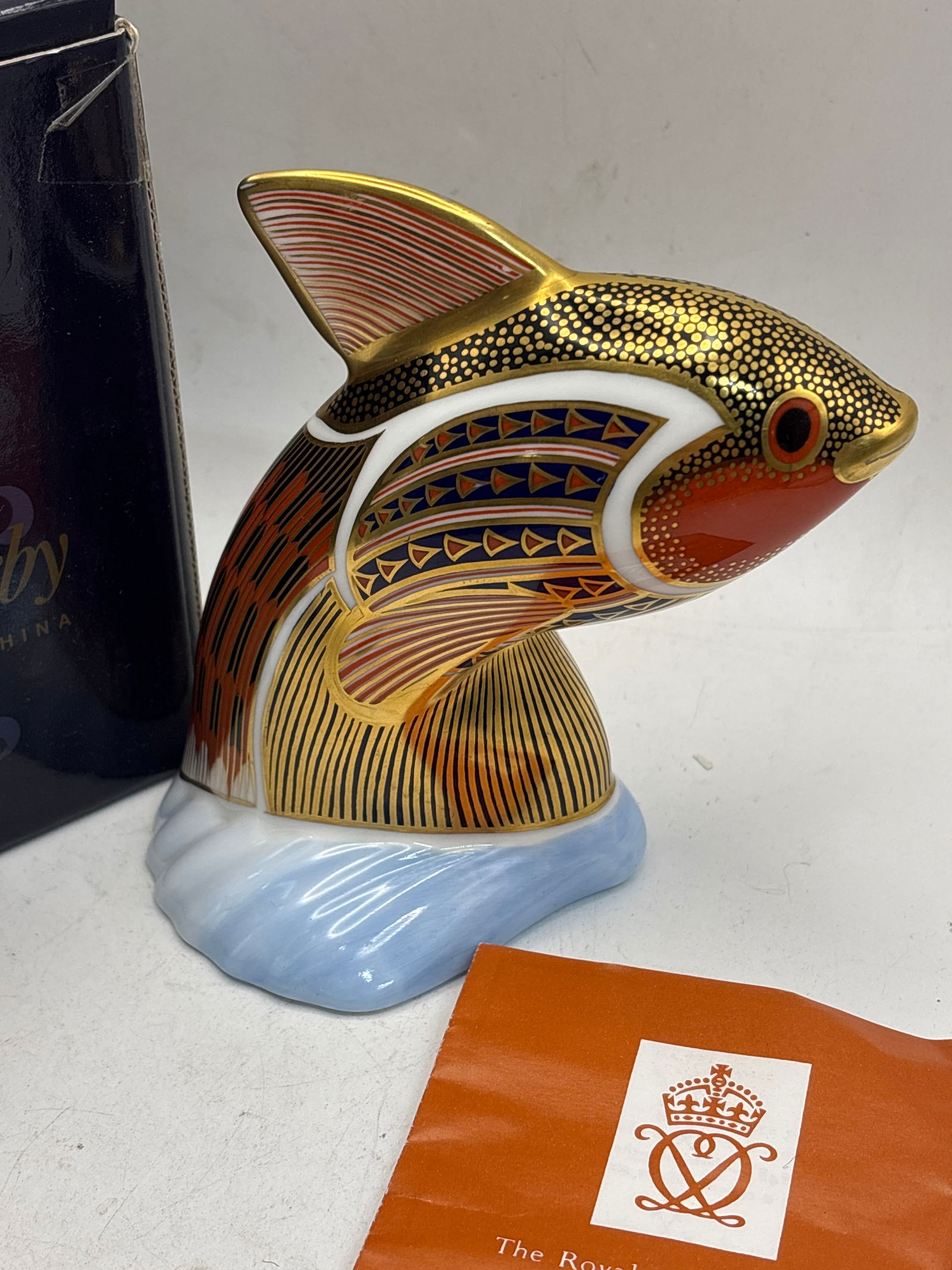 Tropical Fish ‘Guppy’ Royal Crown Derby 5 inch paperweight: Royal Crown Derby "Guppy" tropical fish paperweight in fine bone china, decorated in their signature Imari pattern with 22-carat gold embellishments. The figurine depicts a fish leaping out of blue-pa