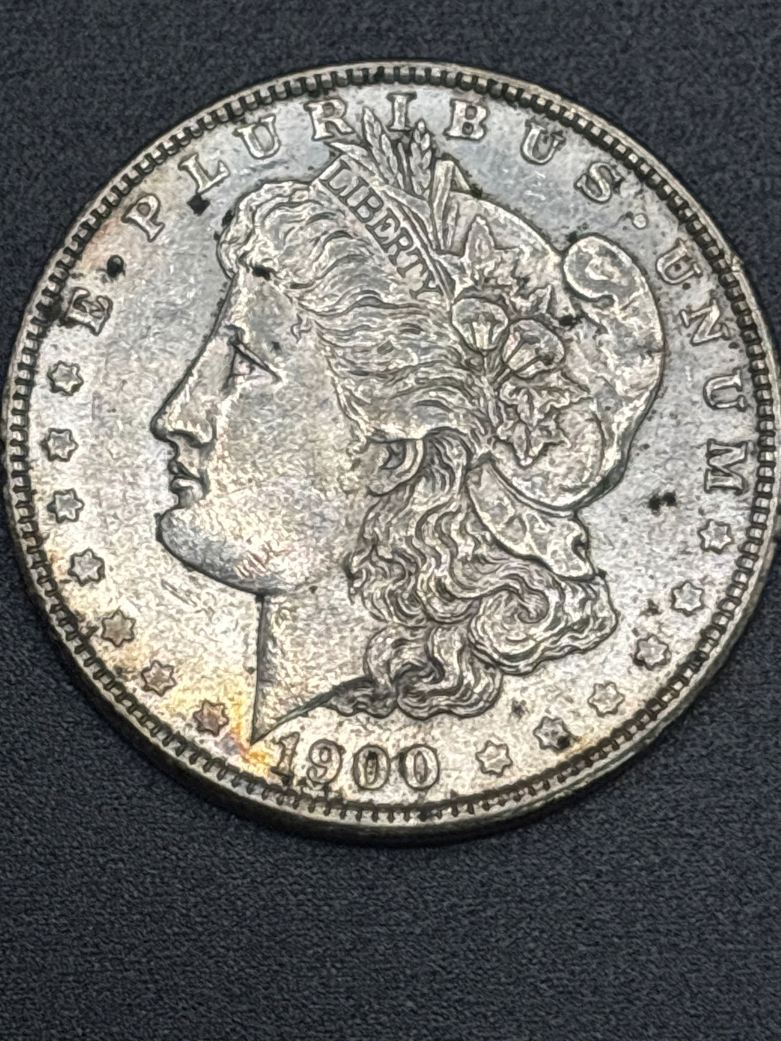 Dated 1900 original Morgan American silver one dollar coin: 1900 Morgan American silver one dollar coin: Contains 0.7734 troy ounces of silver and is composed of 90% fine silver. Weight: Weighs approximately 26.73 grams. History: Designed by George T. Morgan,