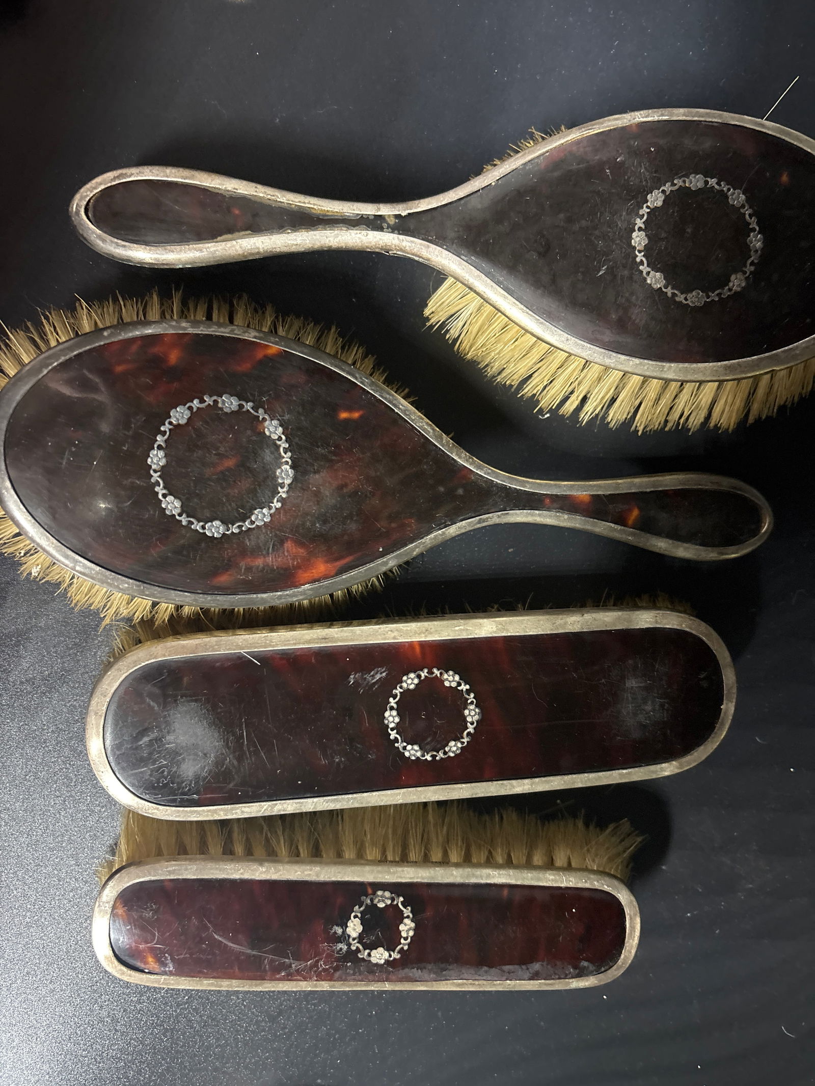 Four piece Harrod’s retailed English sterling & shell vanity brush set: set of antique silver and tortoiseshell brush set, likely from a dressing table set, featuring hallmarks and intricate silver piqué work. Material: Made with sterling silver mounts and tortoiseshell