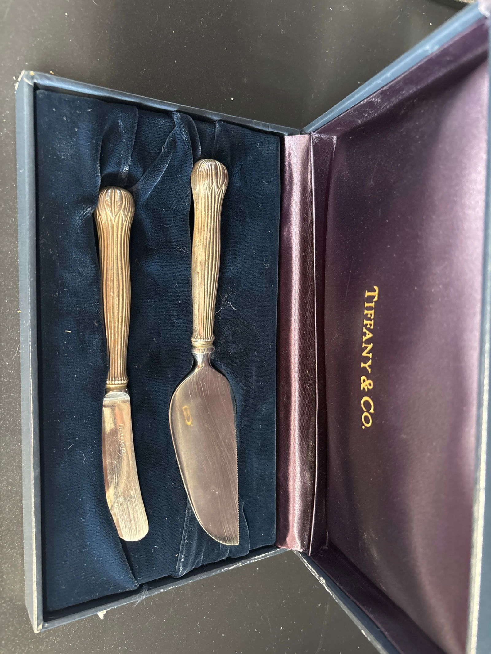 Tiffany & Co. sterling silver cheese serving set: Tiffany & Co. sterling silver cheese serving set, which includes a knife and a spreader, often found in patterns like "Lotus" or "Louis Comfort". Brand: Tiffany & Co.Material: Sterling SilverSet Compo