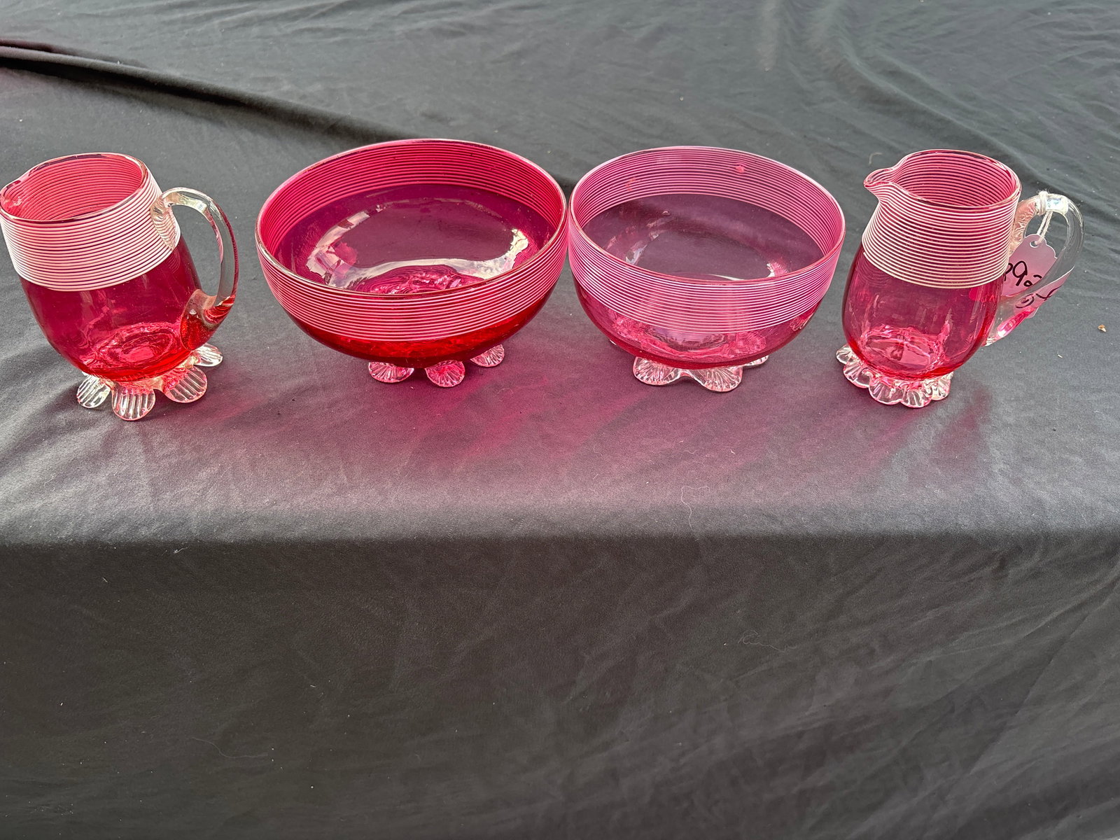 Four Victorian-era Steven’s & Williams cranberry glass jug & bowls: Four Victorian-era cranberry glass jug & bowls, likely produced by the British firm Stevens & Williams. It features a distinctive pink-red color achieved by adding gold salts to the glass. The pitcher