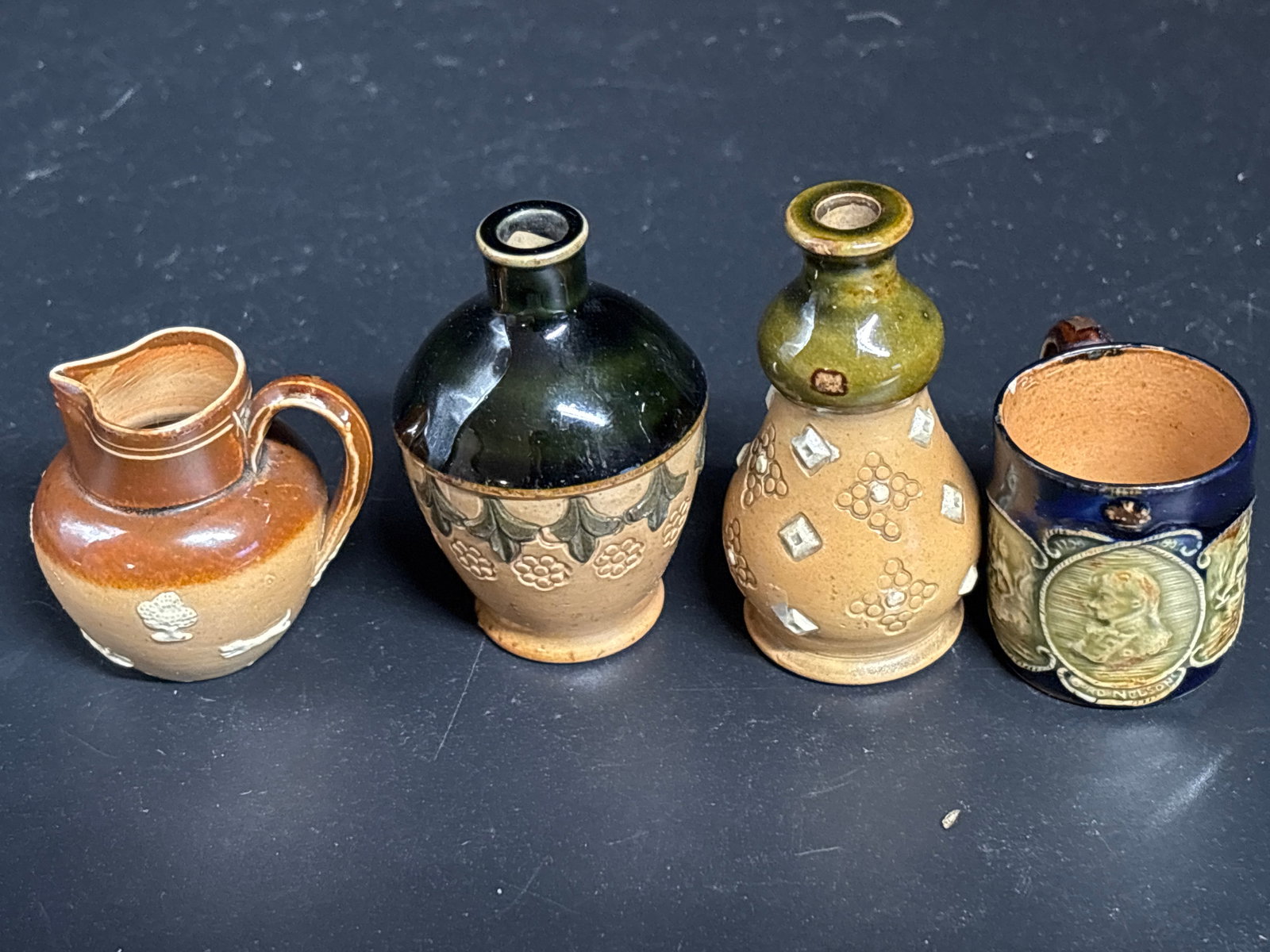 Rare Admiral Lord Nelson Doulton Lambeth stoneware miniature mug & three others: Rare antique Doulton Lambeth stoneware 1&1/2 inch miniature mug, likely produced around 1905 to commemorate Admiral Lord Nelson. Manufacturer: Doulton Lambeth (London, England). Design: Features relie