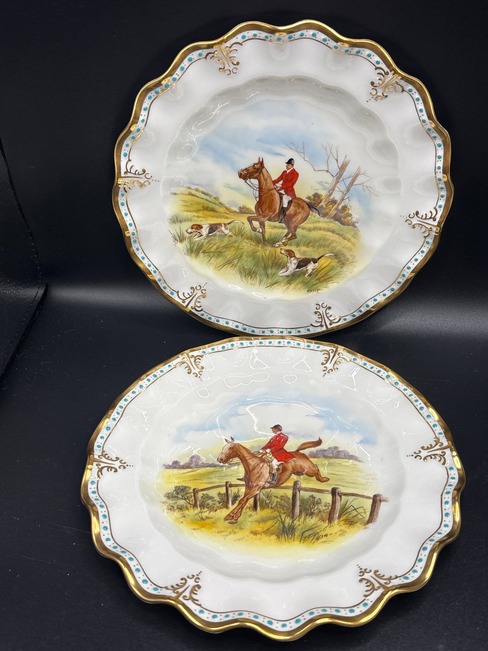 Pair wavy edge Hunting scene Royal Crown Derby bone china 8 inch plates: Pair wavy edge Royal Crown Derby bone china 8 inch cabinet plates featuring a hand-painted fox hunting scene with a rider and hounds.Design: The plate has a scalloped or fluted edge with a 22-karat go