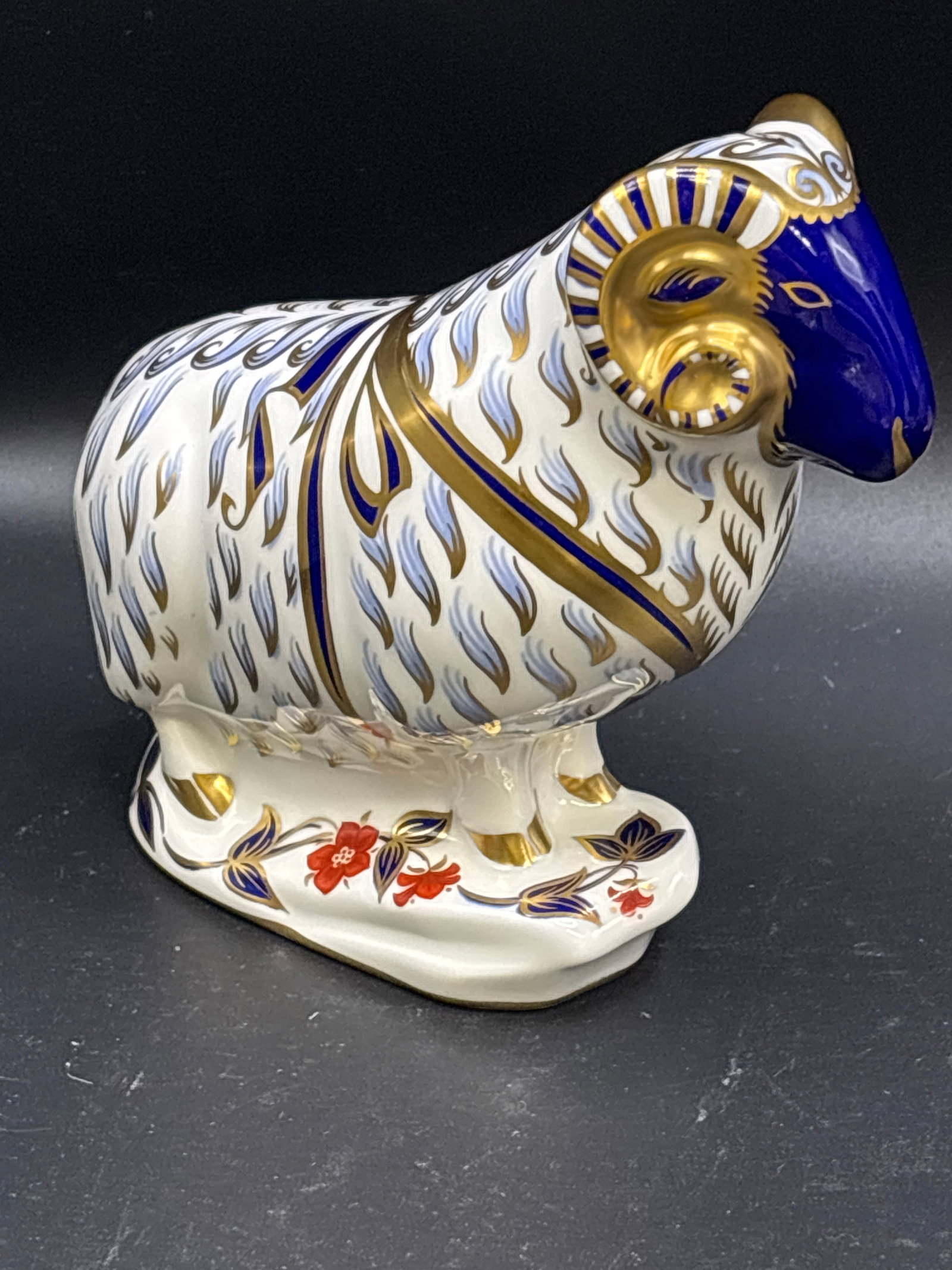 Large 7 inch Royal Crown Derby bone china paperweight: Royal Crown Derby Ram paperweight featuring a white porcelain body with blue and gold Imari-style patterns.Design Details: The figurine features intricate gold, blue, and red floral designs with a dis
