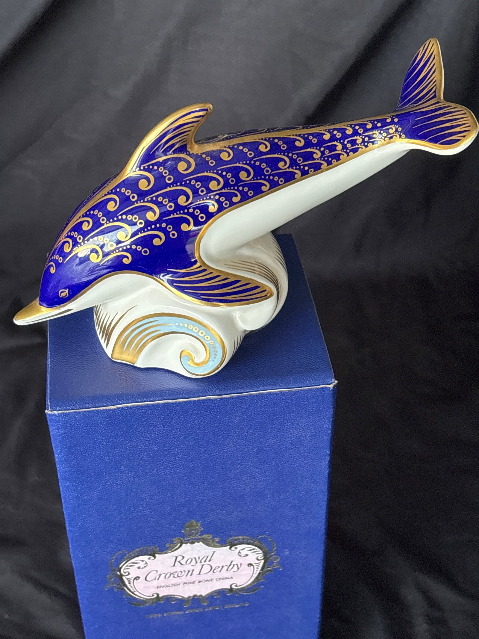 7 inch Royal Crown Derby Dolphi fine bone china paperweight: First quality. Gold stopper. With box. Large 7 inch Royal Crown Derby Imari Dolphin paperweight, hand-painted with cobalt blue and 22K gold accents.Design: The dolphin is depicted in a leaping pose, a