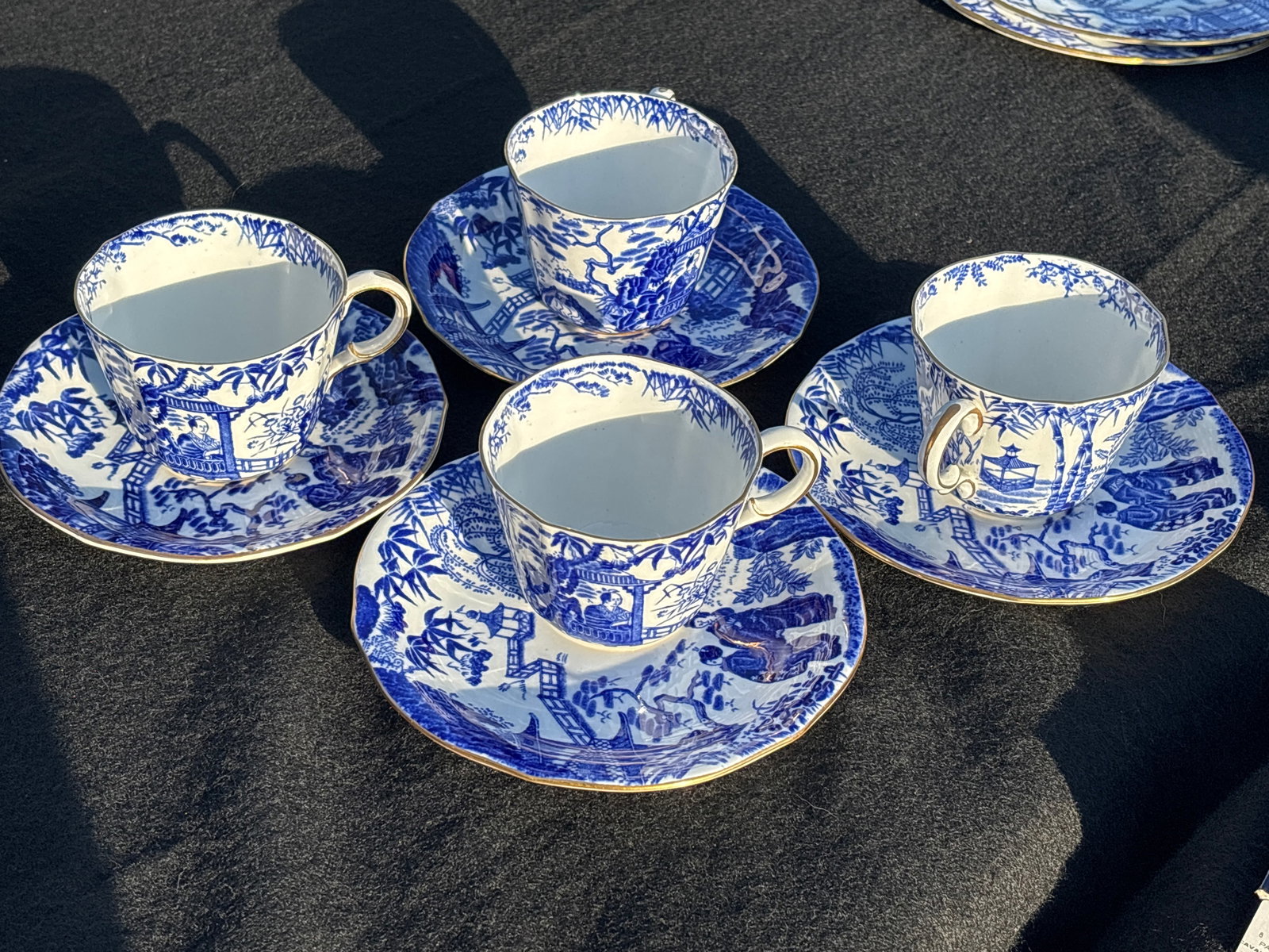 Four Royal Crown Derby tea cups and saucers in the popular "Mikado" pattern: Royal Crown Derby teacup and saucer in the popular "Mikado" pattern. This classic design features a blue transferware scene of pagodas, bamboo, and bridges, inspired by traditional Japanese art. 2&3/4