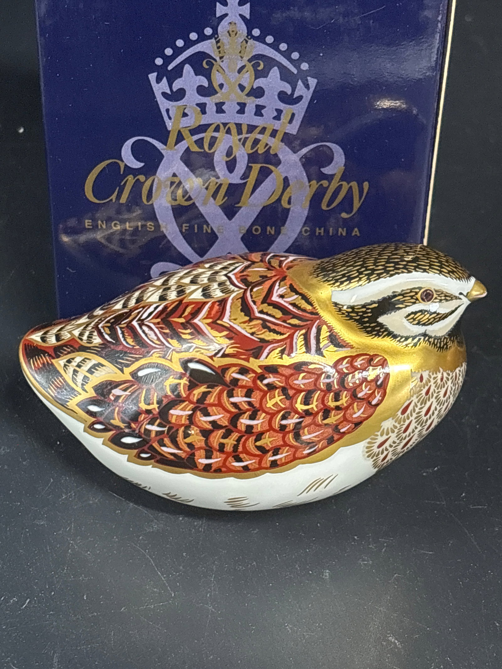 ‘Dappled Quail’ Royal Crown Derby Imari bone china 4 inch paperweight: Gold stopper and box. Royal Crown Derby Dappled Quail porcelain paperweight.Design: Features intricate brown, white, and black patterned feathers with 22-karat gold gilt highlights.Stopper: Includes a