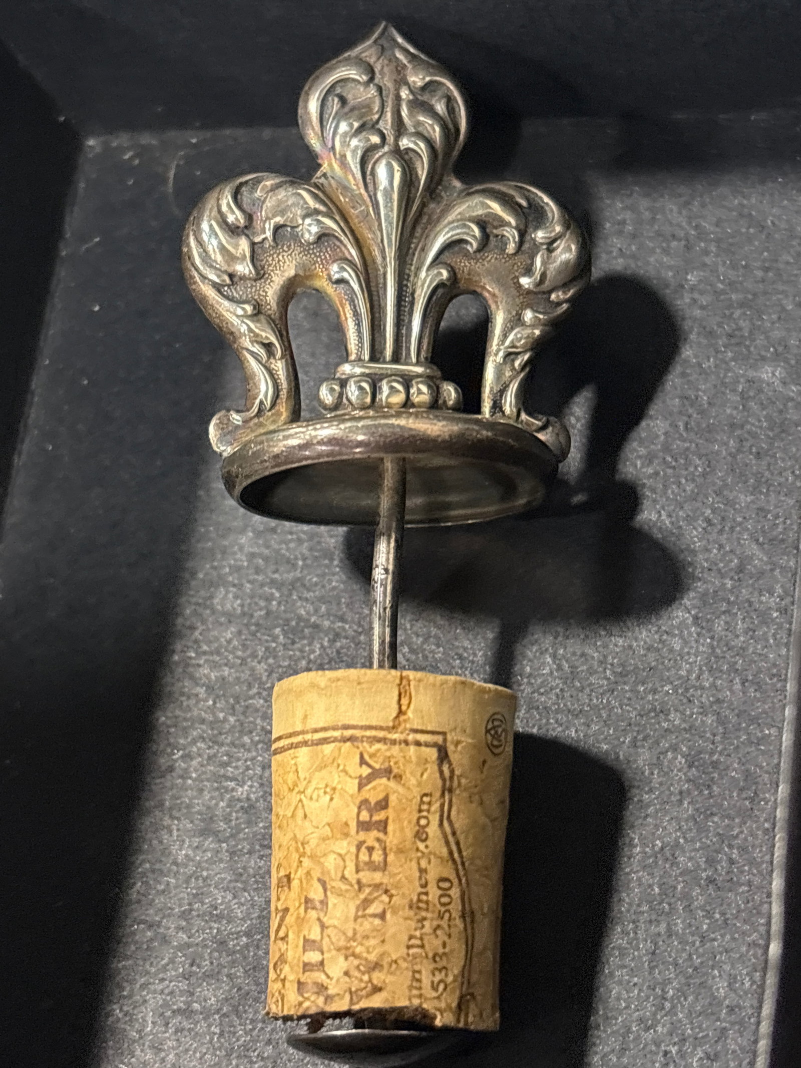 Sterling silver dated 1866 Fleur-de-lis shape bottle stopper: Sterling silver dated 1866 wine stopper featuring a metal fleur-de-lis design affixed to a cork base. It appears to be a vintage or collectible wine accessory rather than a modern functional item