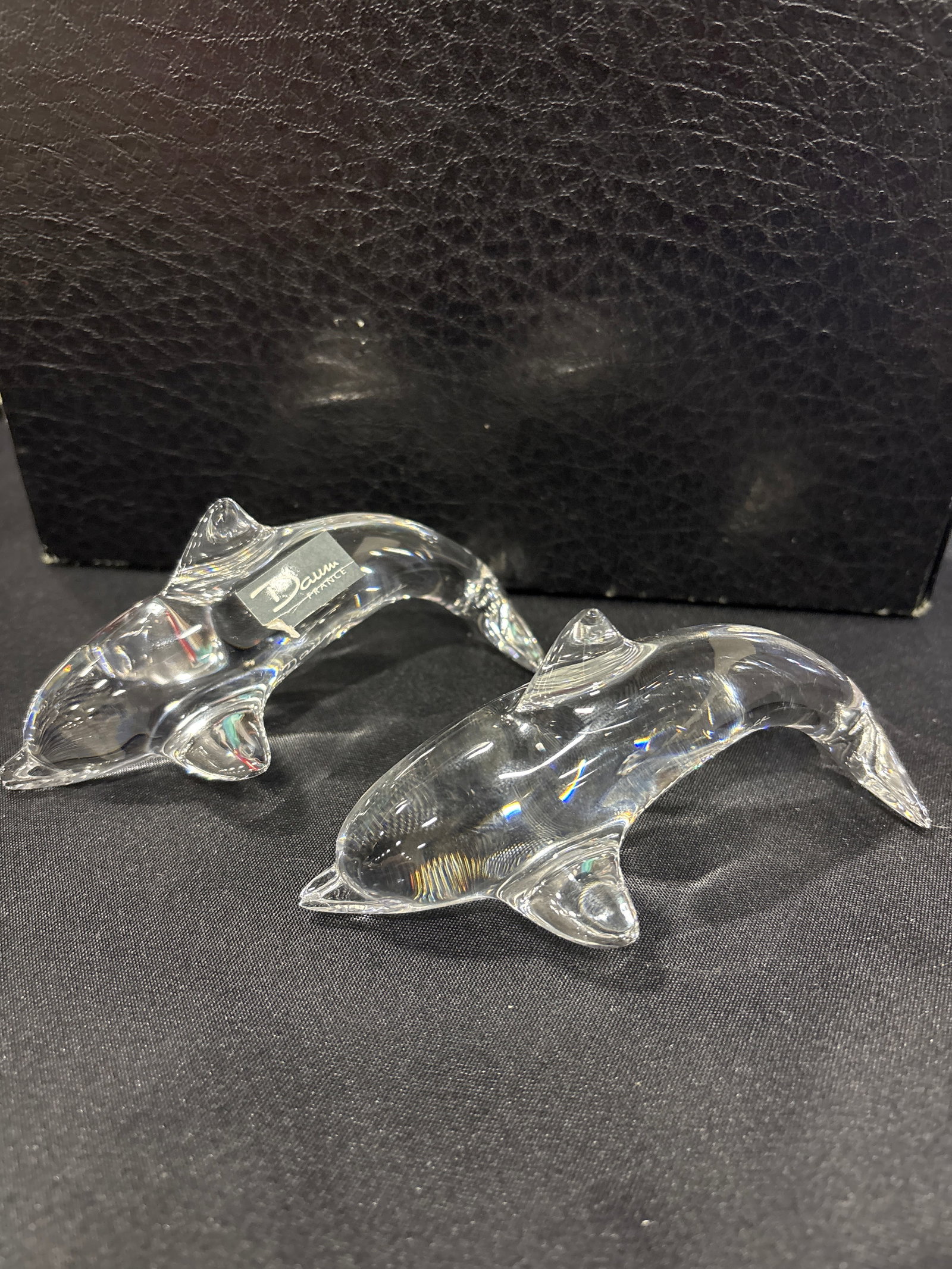 Two signed Daum France crystal glass dolphin figurines: Two Daum France crystal glass dolphin figurines, a collectible art glass piece featuring a clear, streamlined design and the brand's signature marking. Brand: Daum FranceMaterial: Clear Crystal GlassI