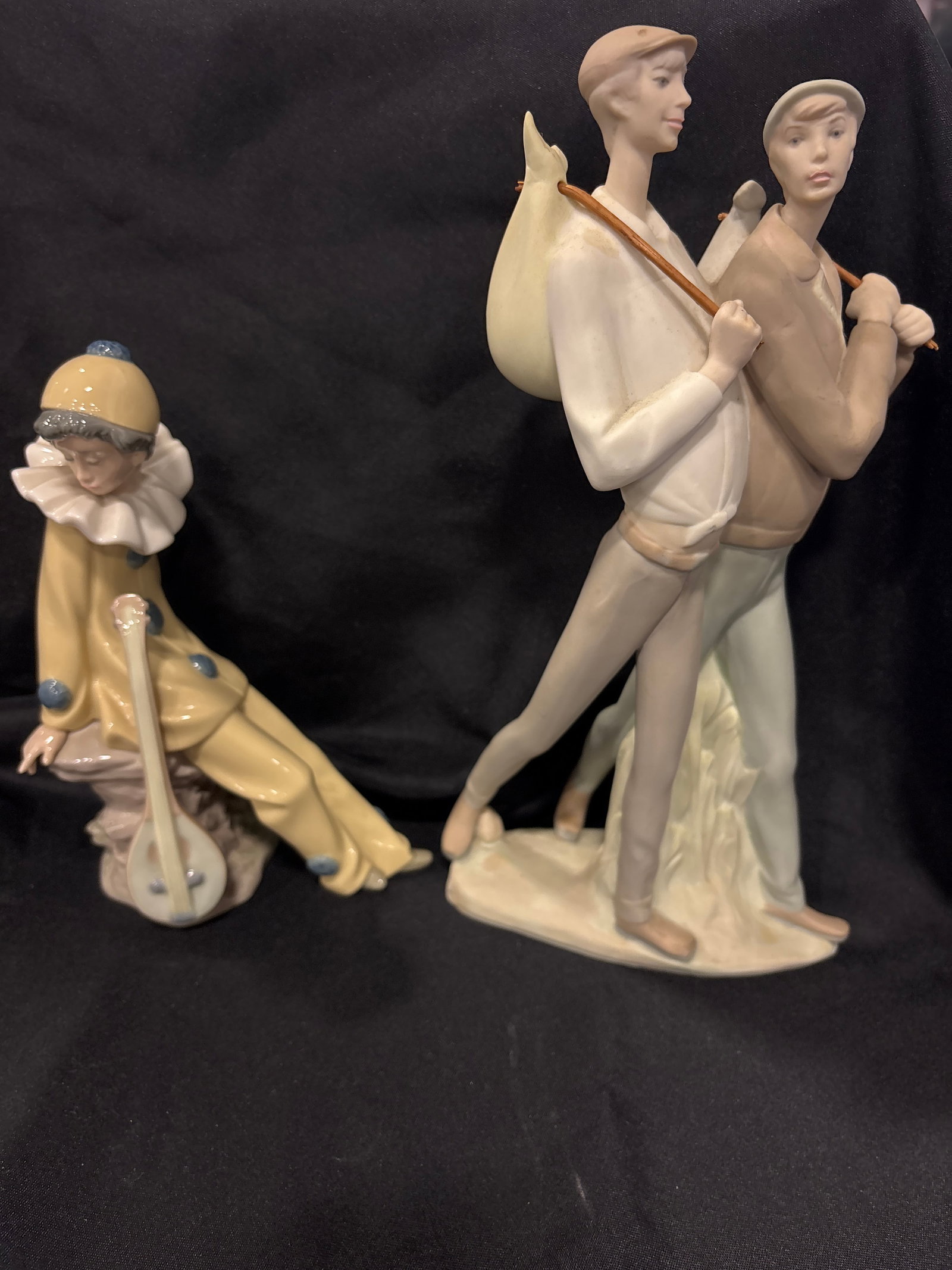 Two Nao by Lladro Spanish porcelain statues: Two Nao by Lladro Spanish porcelain statues. A traveling men & a “Wandering Minstrel" clown figurine by Nao by Lladro, which features a seated clown playing a mandolin. Brand: Nao by Lladro (a brand