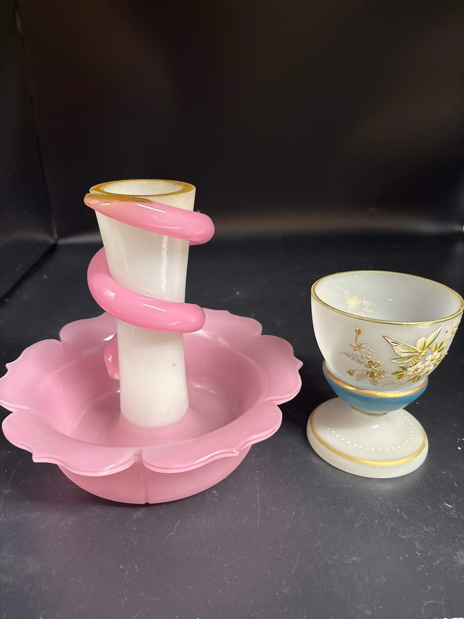 Two Victorian art glass vases: Two Victorian art glass vases.pink and white glass candlestick holder, resembling a floral base with a snake-like coil around the stem and a vintage or antique egg cup, likely made of opaline glass.