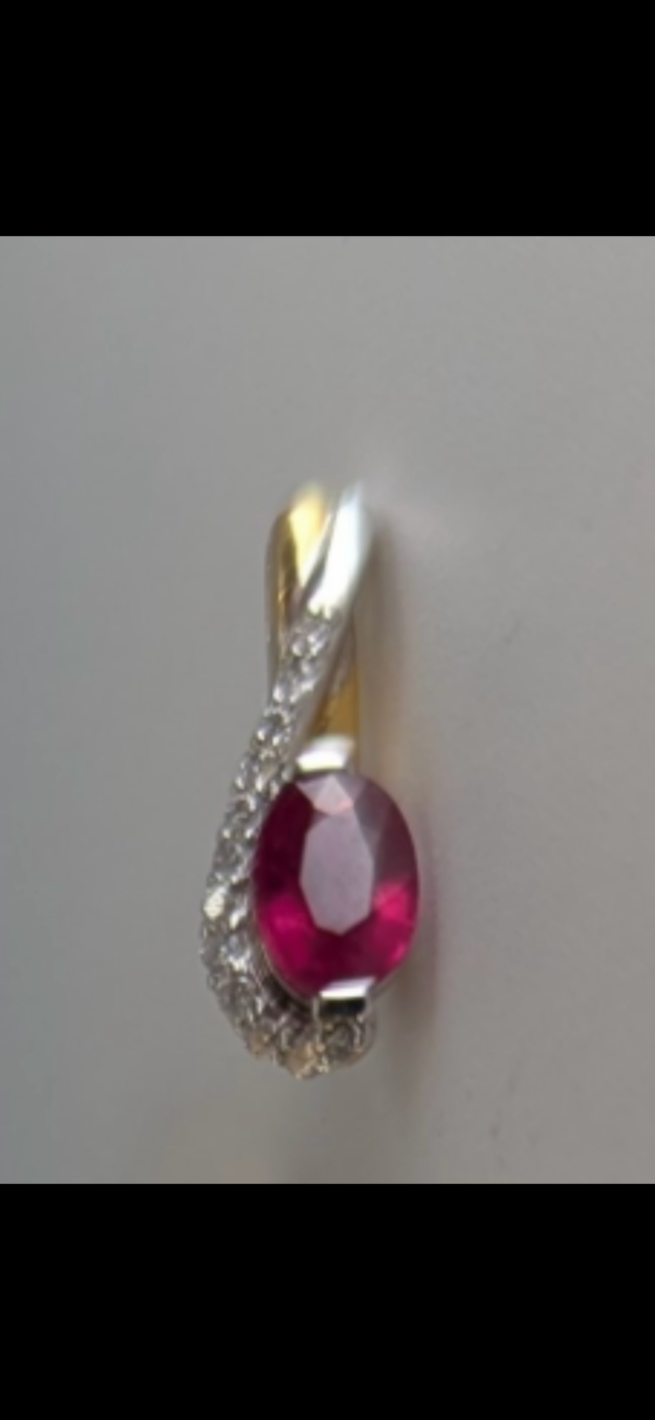 18ct gold 0.50ct (1/2 carat) oval brilliant ruby & diamond set pendant; 1.2 grams: An 18ct gold 0.50ct (1/2 carat) oval brilliant cut treated pink ruby and melee round brilliant cut diamond set pendant, stamped 750, 1.2g gross. With box.
