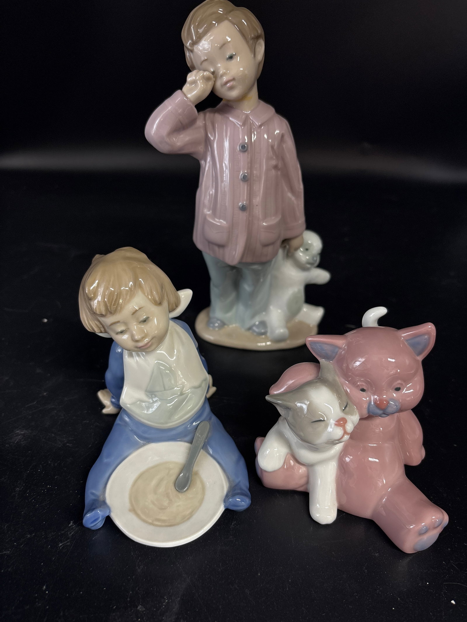 Three Nao by Lladro handmade Spanish porcelain figurines: porcelain figurine titled "A Friend for Cuddles" (model #1461) produced by Nao, a brand under Lladró, "I'm Full" by Nao by Lladro, featuring a baby boy sitting with a bowl and spoon, and "Sleepy Head