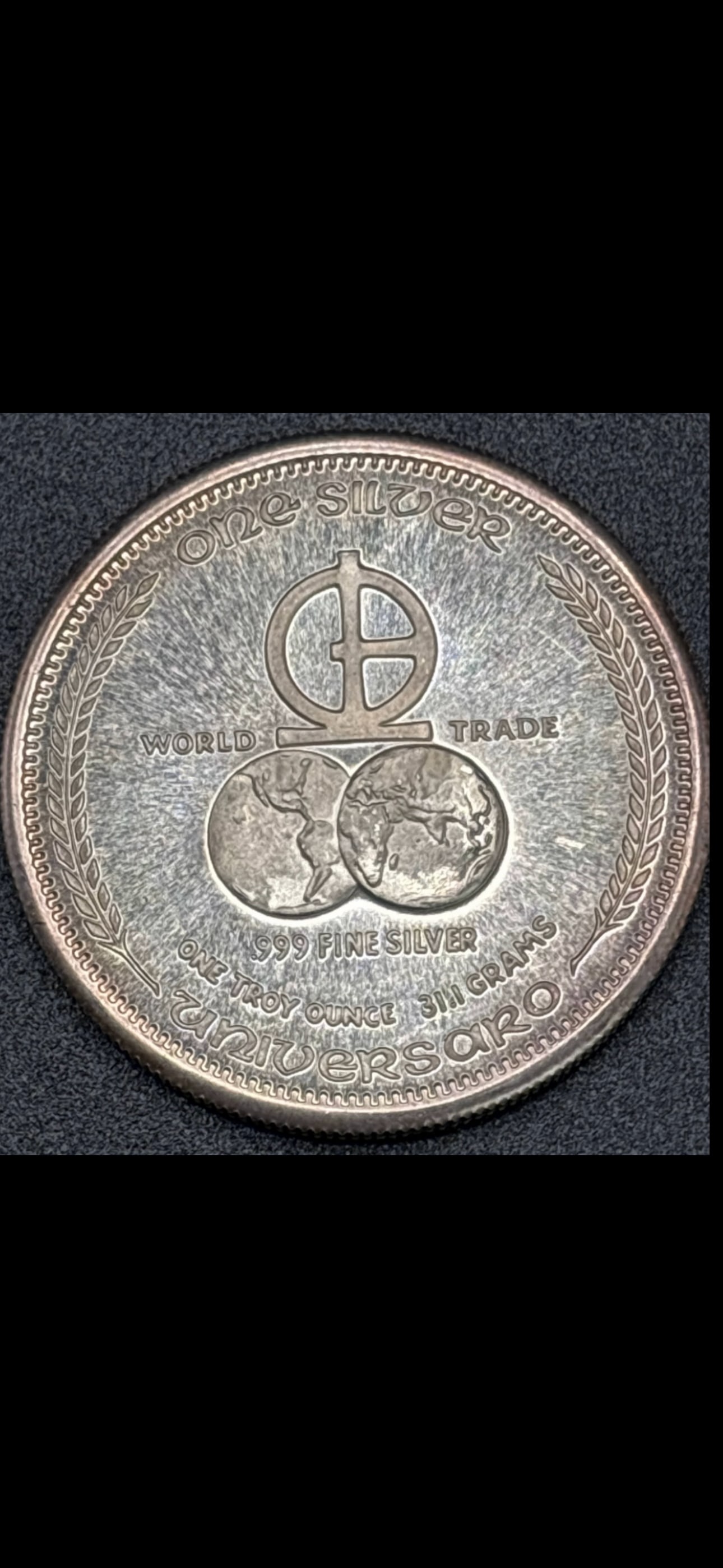 1 ozt .999 fine silver 1973 Universaro World Trade coin; 31.1 grams: 1973 Universaro World Trade 1 ozt .999 silver round. Composition: Contains 1 Troy ounce of .999 fine silver. Design: The obverse features the Scales of Justice above five human faces, representing a m