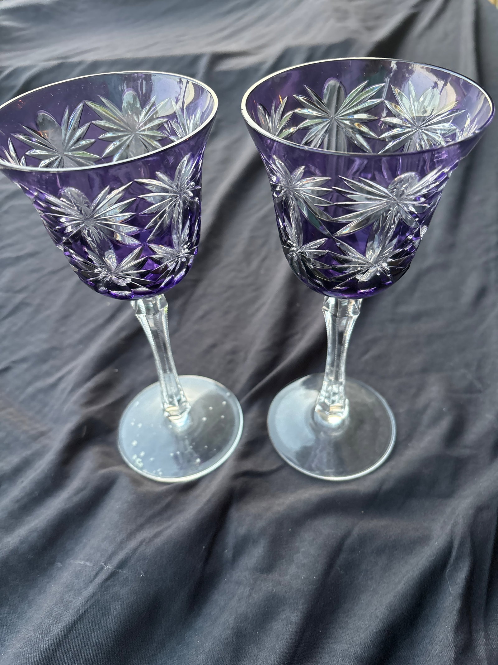 Unsigned pair of purple crystal goblets cut-to-clear crystal 8&3/8 inch wine hocks: amethyst purple crystal wine goblets featuring a cased cut-to-clear pattern.Design Details: The glasses have a deep purple overlay that has been wheel-cut to reveal clear glass underneath, forming int
