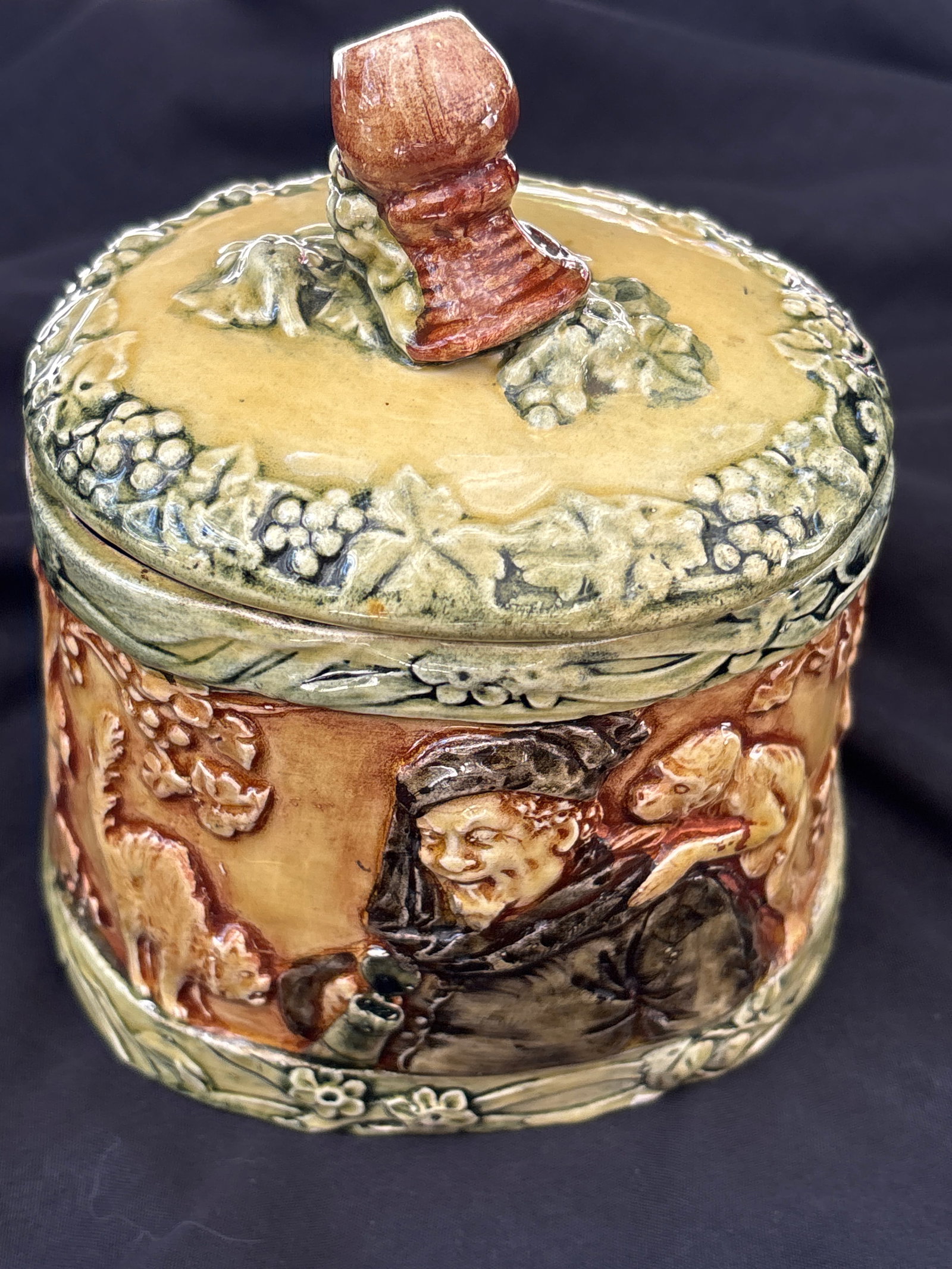 antique Majolica tobacco jar featuring a relief design of a monk in a wine cellar: antique Majolica tobacco jar featuring a relief design of a monk in a wine cellar. These types of lidded ceramic jars were popular in the 19th and early 20th centuries as decorative humidors for stori
