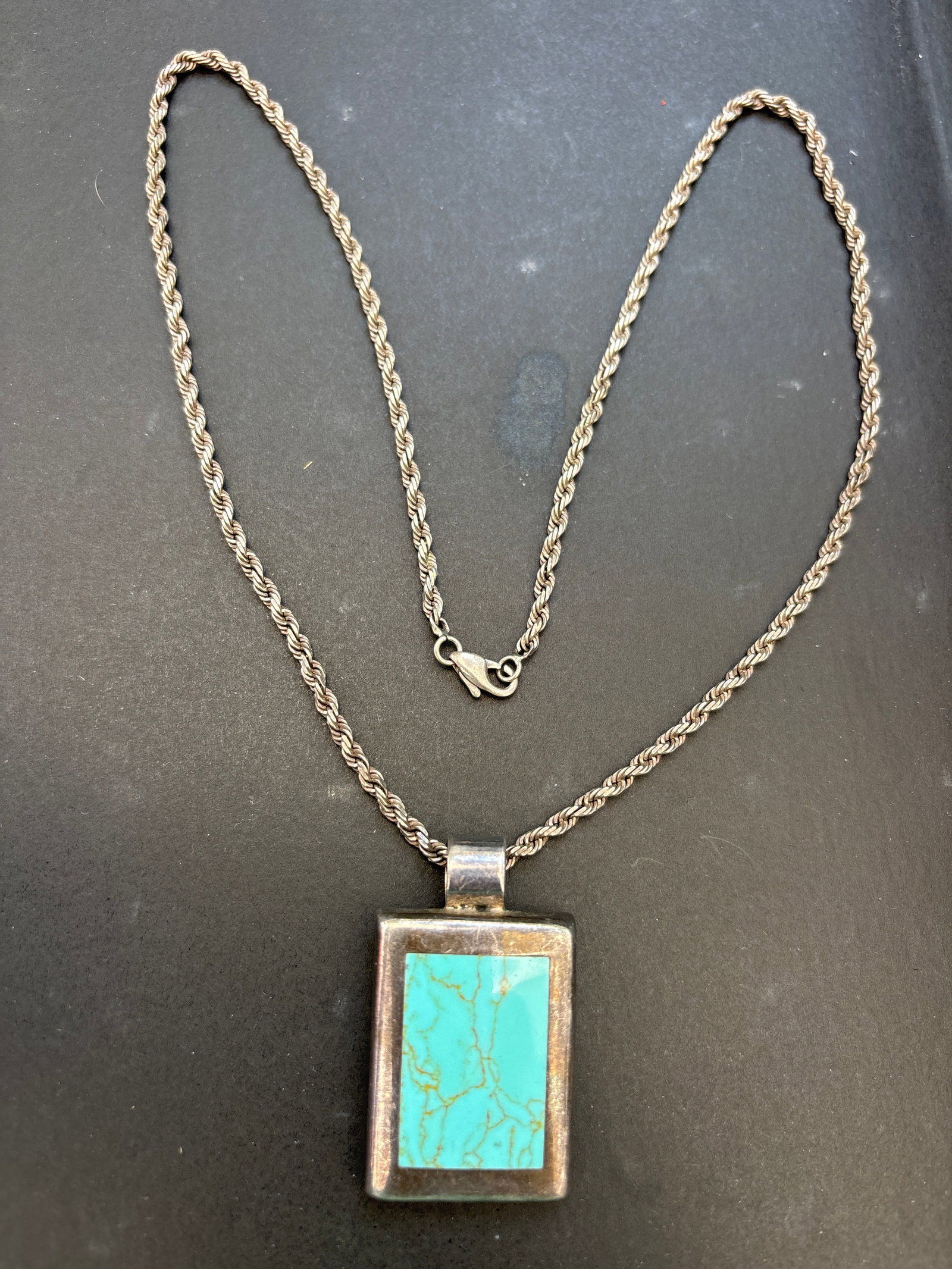 Vintage sterling silver chain & pendant bezel-set, rectangular turquoise stone; 32 grams: Vintage sterling silver pendant featuring a bezel-set, rectangular turquoise stone. Based on its design and visual matches, it is likely a vintage piece of Southwestern or Mexican silver jewelry.Key F