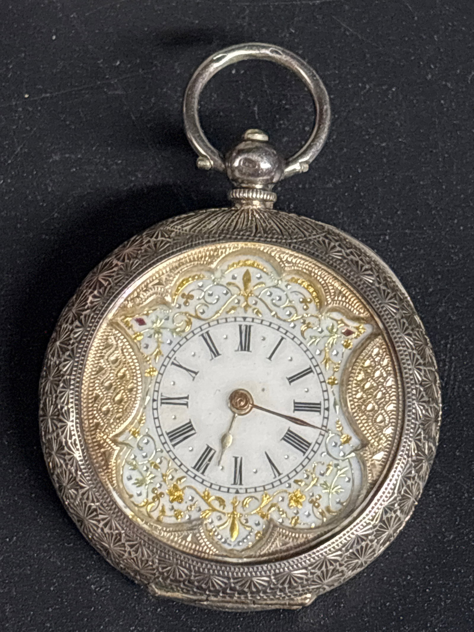 antique .935 silver Swiss pocket watch features an ornate case: antique Swiss pocket watch features an ornate silver case and a detailed gold-toned dial.Design & Materials: The watch is housed in an engraved silver case, made of .935 silver. The face is typically 