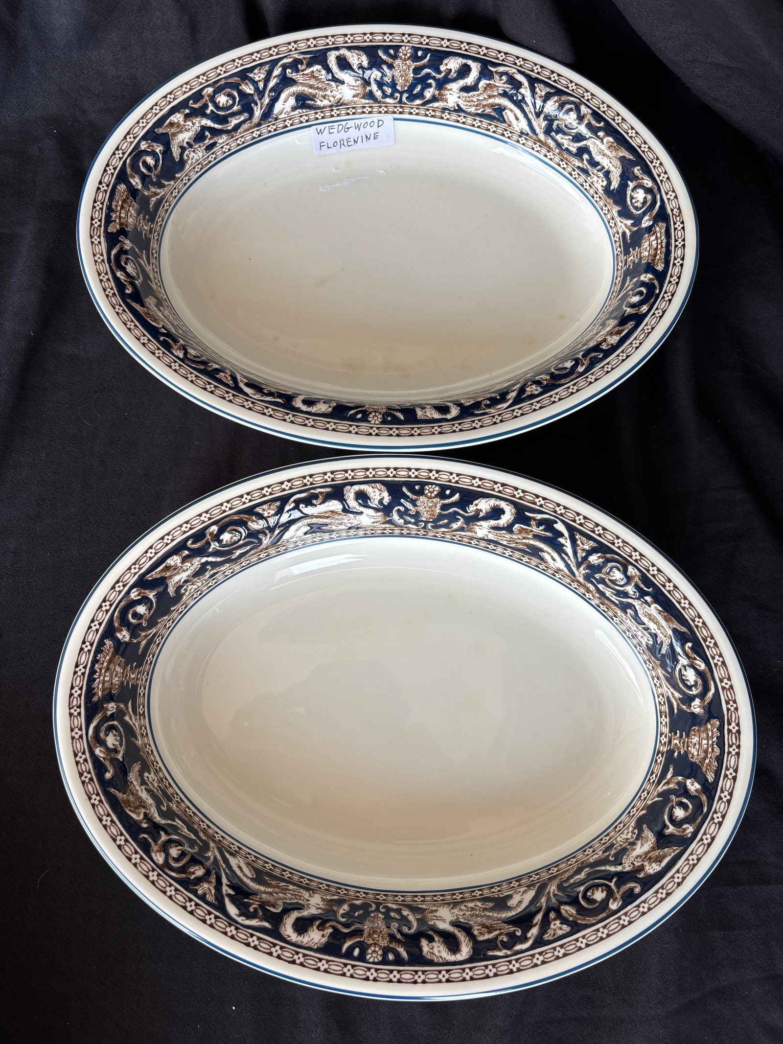 Pair 10 inch oval serving bowls Wedgwood Florentine Dark Blue (W1956): Pair 10 inch oval serving bowls Wedgwood Florentine Dark Blue (W1956) pattern. This classic design is crafted from fine bone china and features a rich cobalt/navy blue rim decorated with mythological 