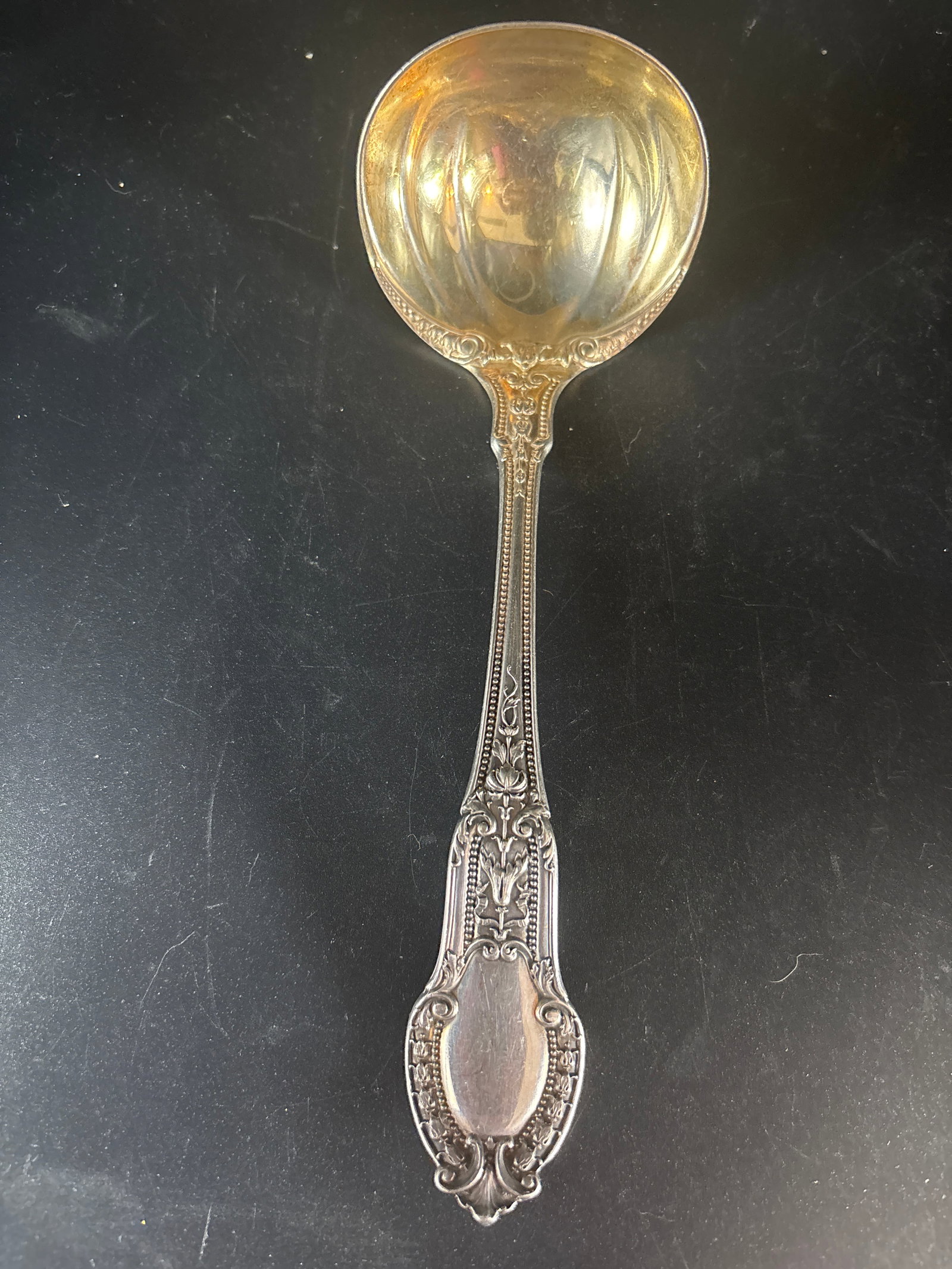 70 grams, Gorham Sterling Silver 7 inch serving spoon in Tuileries pattern: 70 grams, Gorham Sterling Silver spoon in the Tuileries pattern, which was introduced in 1906. The specific utensil shown is a sauce or gravy ladle, characterized by its round bowl and typically measu