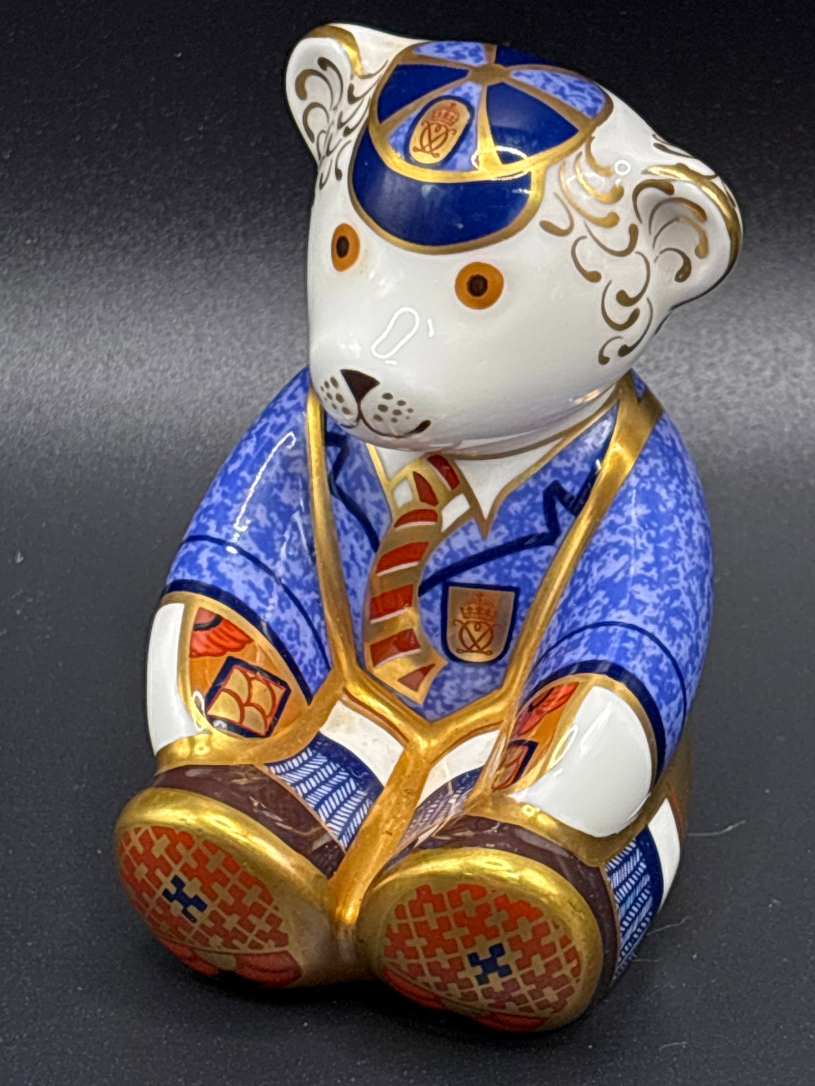 Royal Crown Derby "Schoolboy Teddy" 3 inch paperweight statue: Royal Crown Derby "Schoolboy Teddy" porcelain paperweight, likely produced around 2001.It features intricate Imari-style patterns in blue, red, and gold, depicting a bear in a school uniform.These col