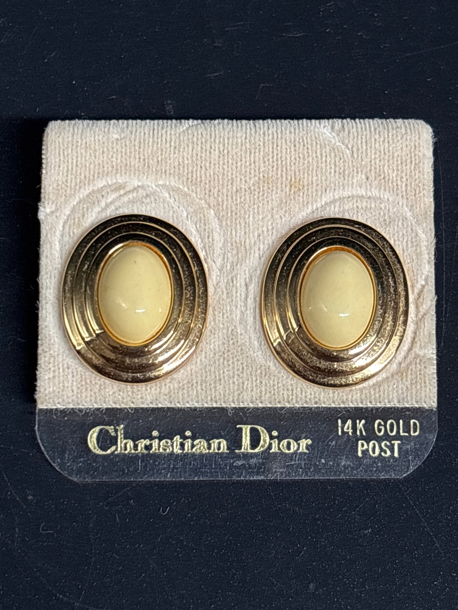 Pair 14 k yellow gold posts vintage Christian Dior earrings: New old stock vintage Christian Dior earrings featuring a cream-colored oval cabochon set in a gold-tone ribbed frame.The earrings are listed as having 14K gold posts, as indicated on the original pac